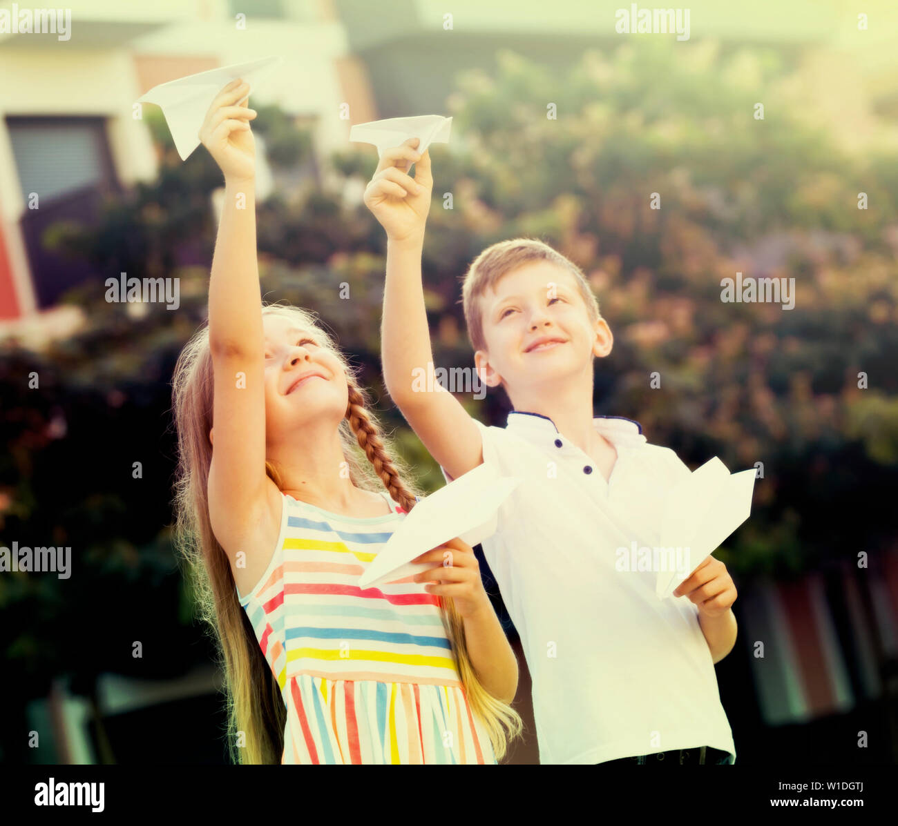 Two smiling kids playing with flying paper planes outdoors Stock Photo ...