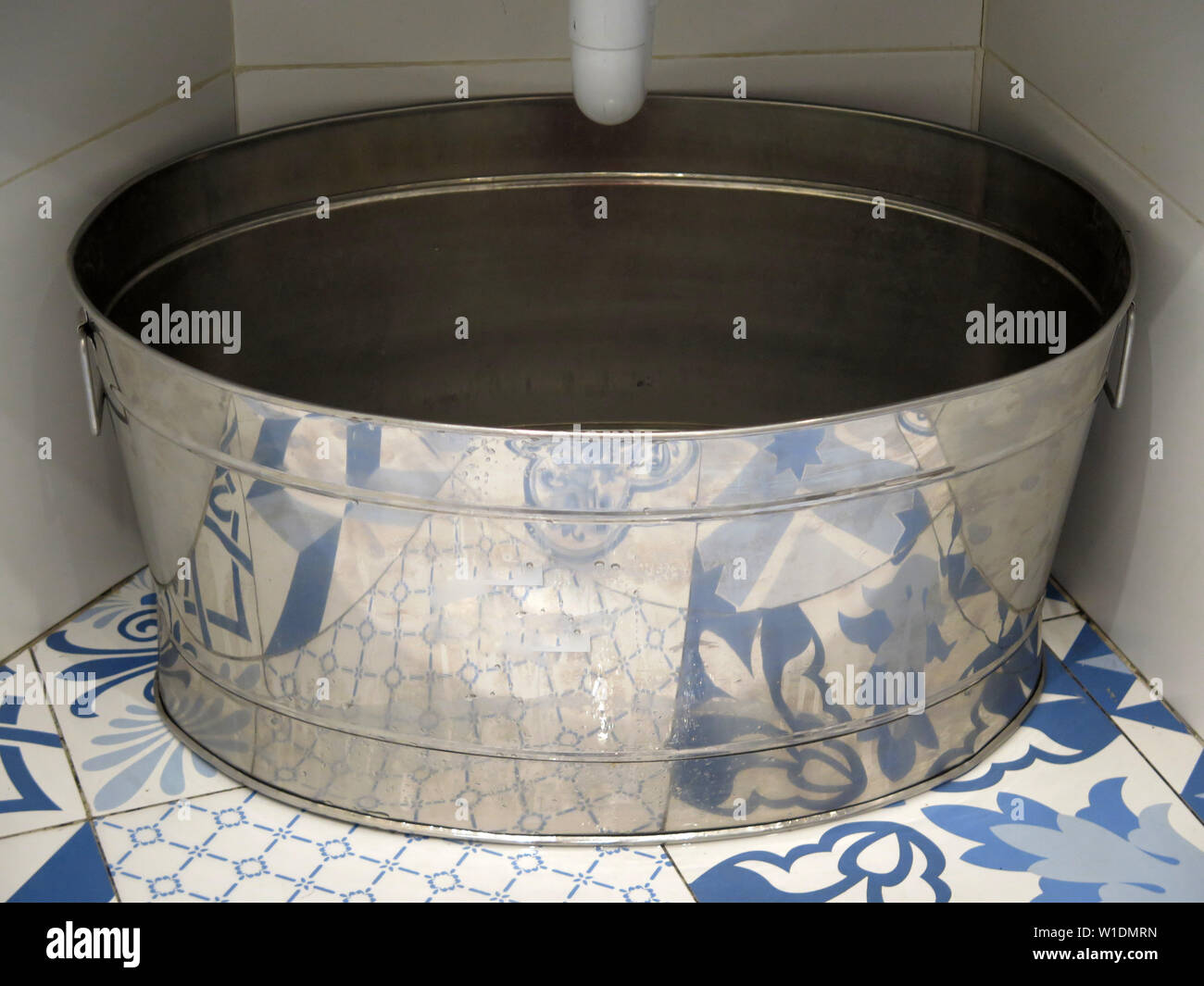 Large zinc tub under ceramic sink in Malaga bar restroom Stock Photo