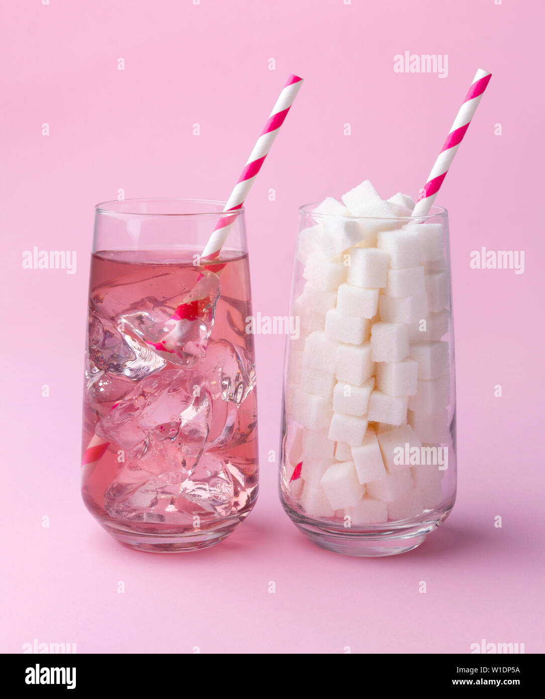 Glass full of sugar cubes and glass of soda water with ice. Unhealthy