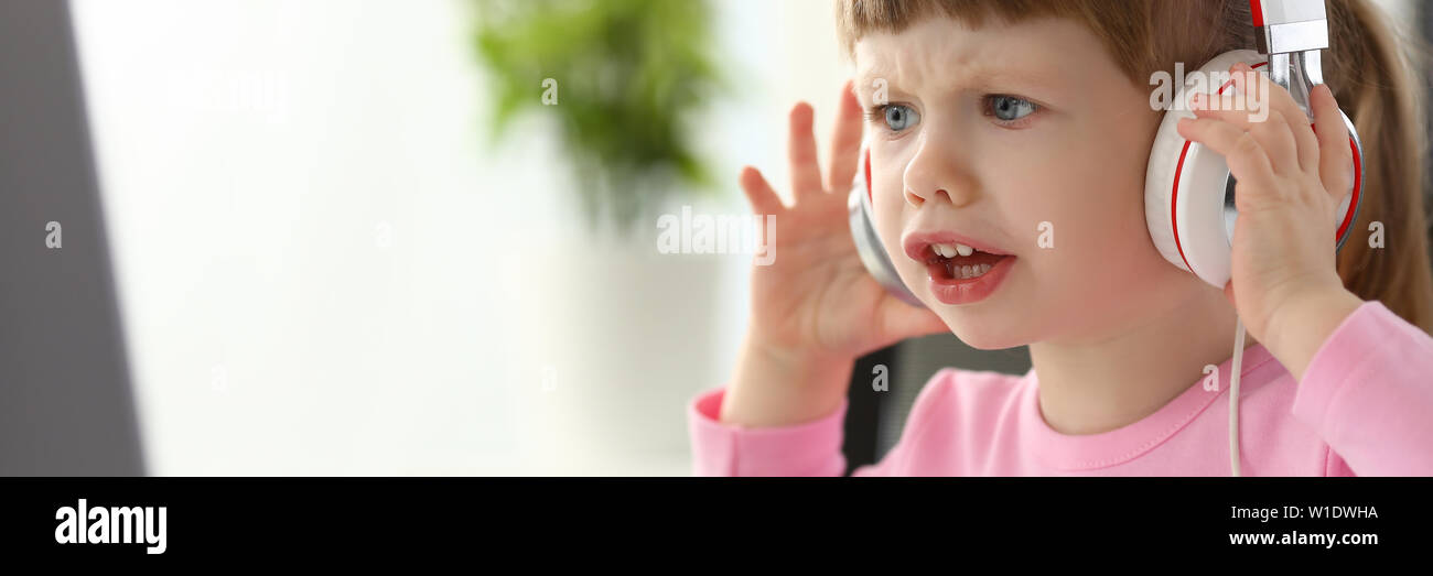 Little girl wearing headphones using computer aggressive articulating Stock Photo