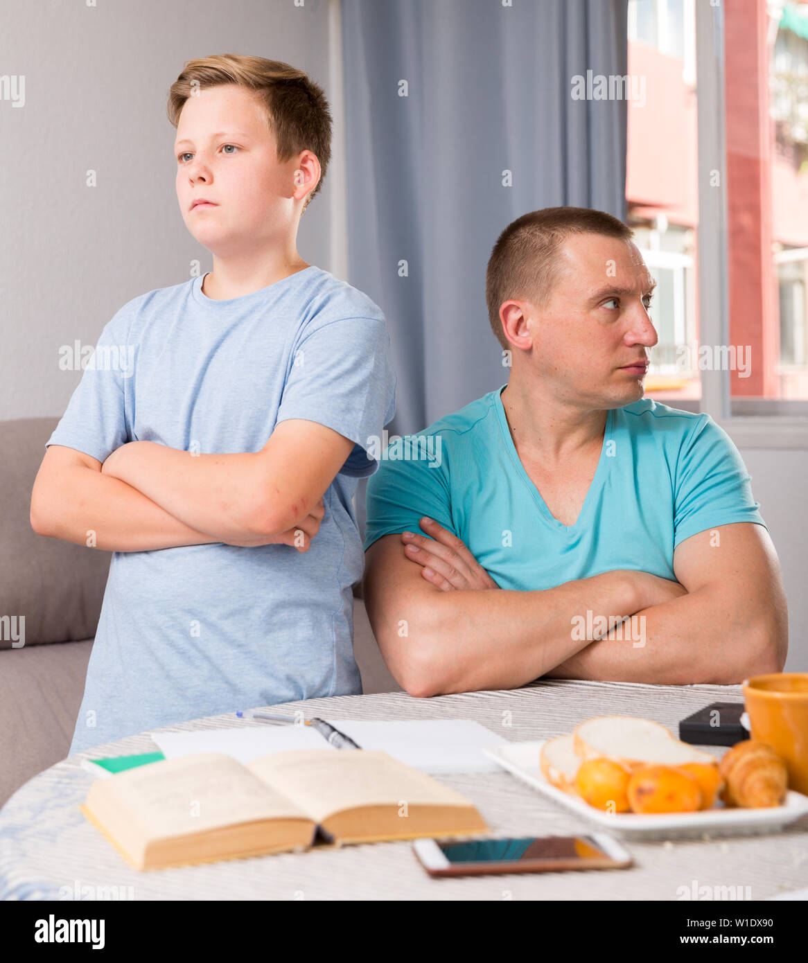 Man is offended and son is not wanting talking with him in time doing homework at the home. Stock Photo