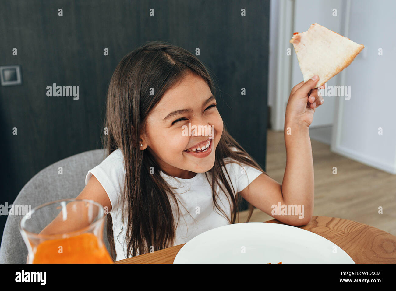 Funny cute little girl eating pizza and laughing Stock Photo
