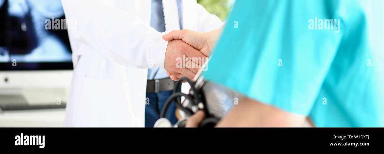 Two doctors in office shaking hands celebrating successful treatment Stock Photo