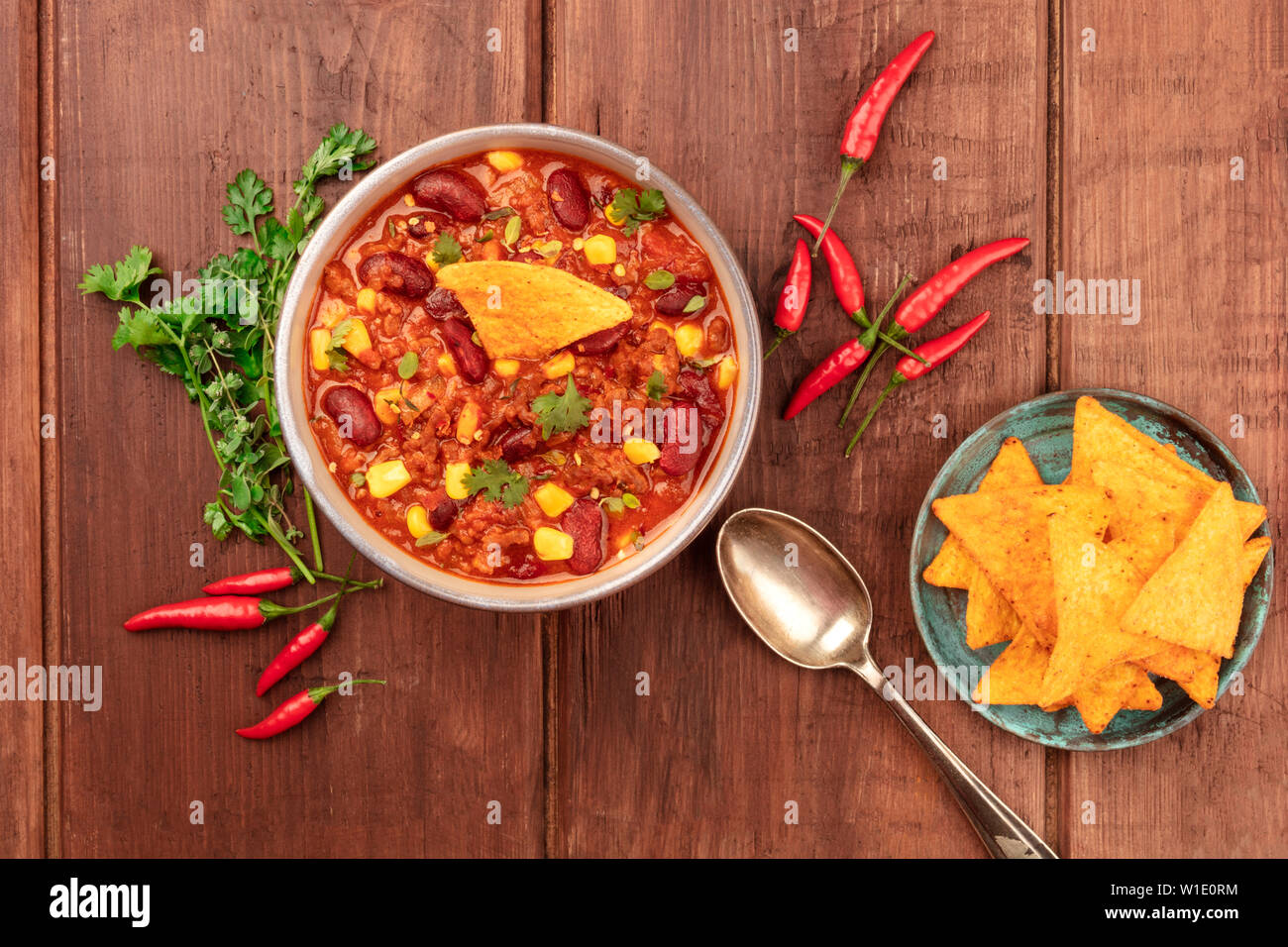 Chili con carne with ingredients, cilantro, oregano, chili peppers, and  nachos, shot from the top on a dark rustic wooden background Stock Photo -  Alamy