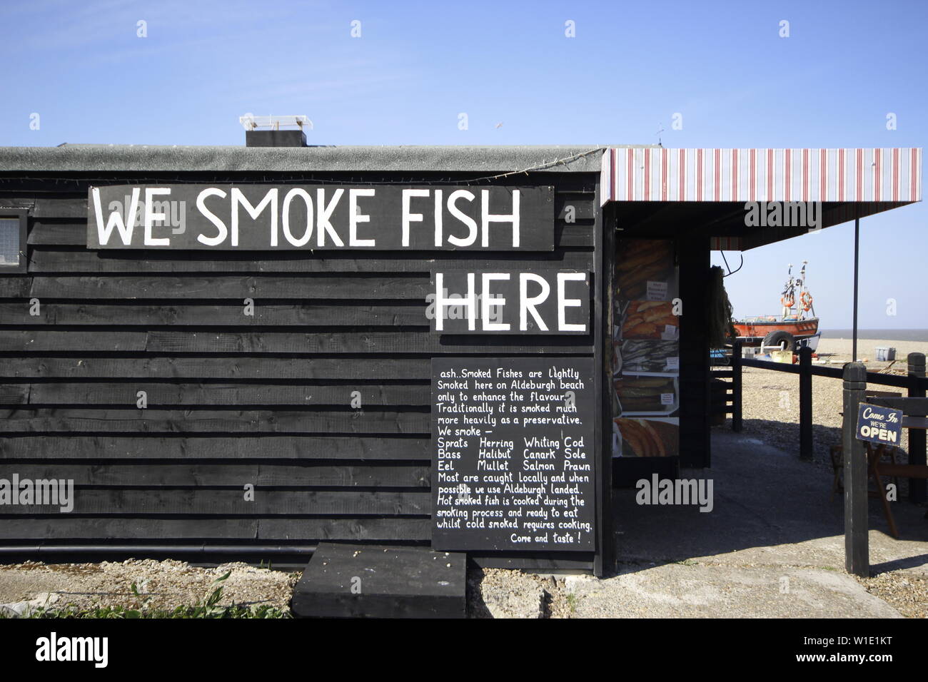 colour image of a wooden fishing shack on the beach with the sign 'We smoke fish here' painted on the outside Stock Photo