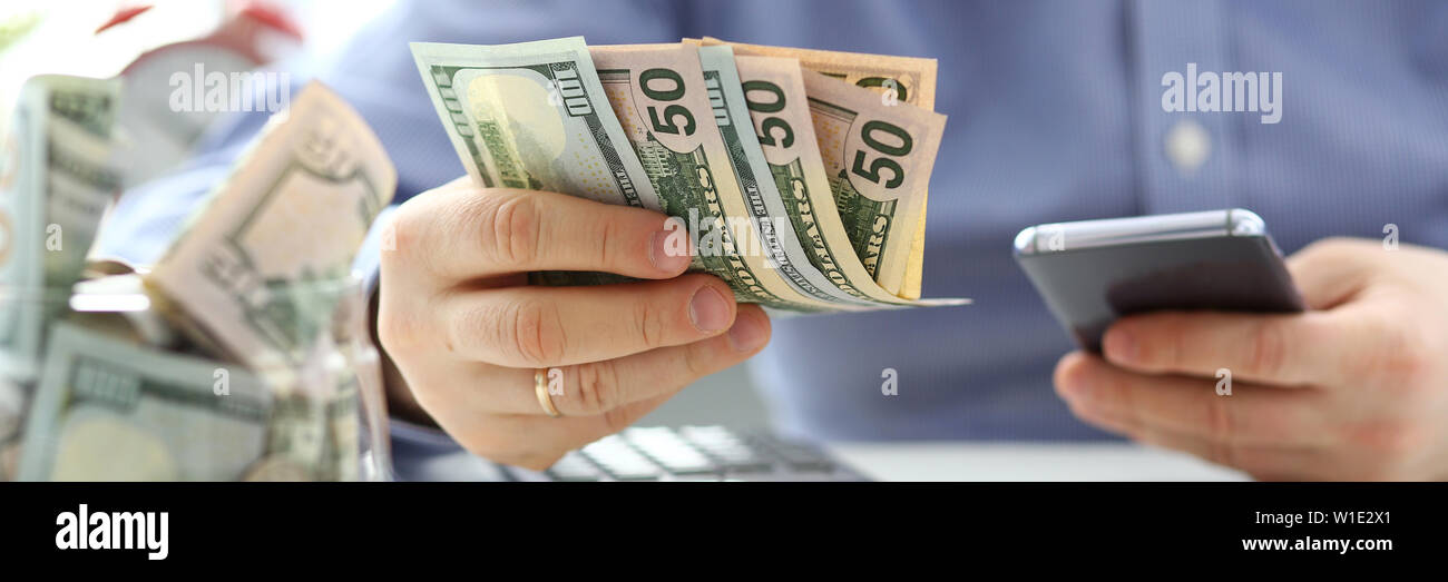 Male hand holding pack of banknotes and cellphone Stock Photo
