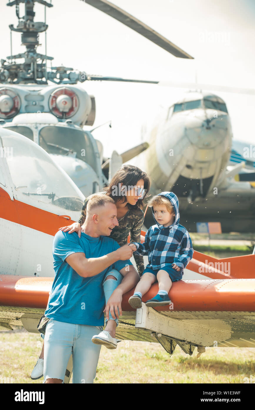 Vacation concept. Happy family enjoy summer vacation at military air show. Child with mother and father sit on plane wing during vacation. Family vaca Stock Photo