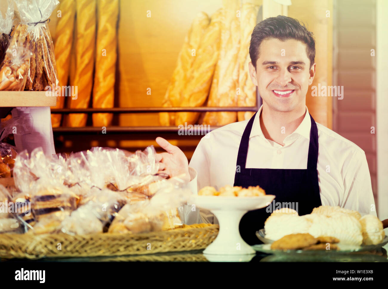 baker selling fresh pastry and baguettes in local bakery Stock Photo