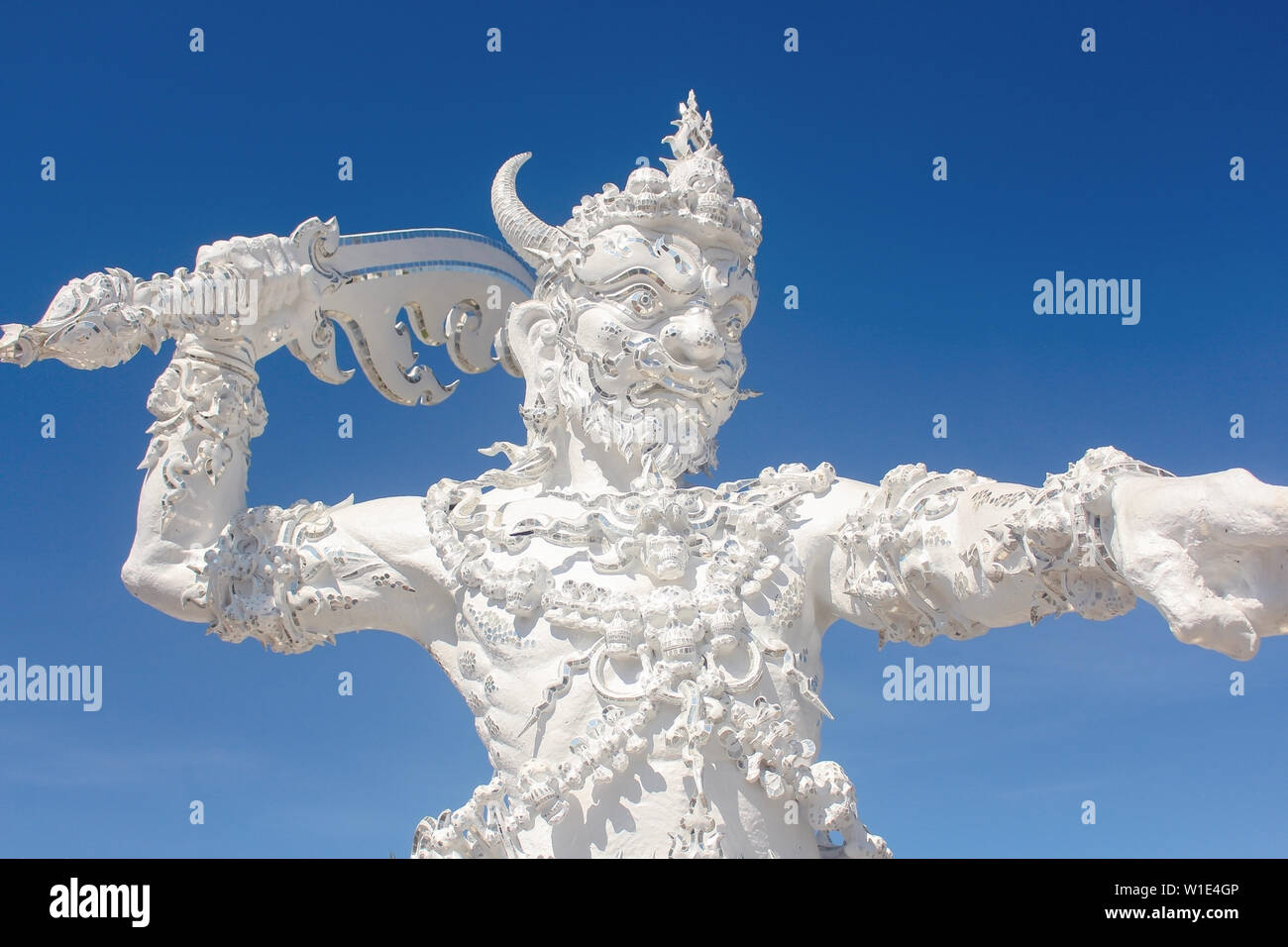 Angel of Death guard statue at the entrance of Wat Rong Khun or White Temple, with fragments of mirrored glass embedded. Stock Photo