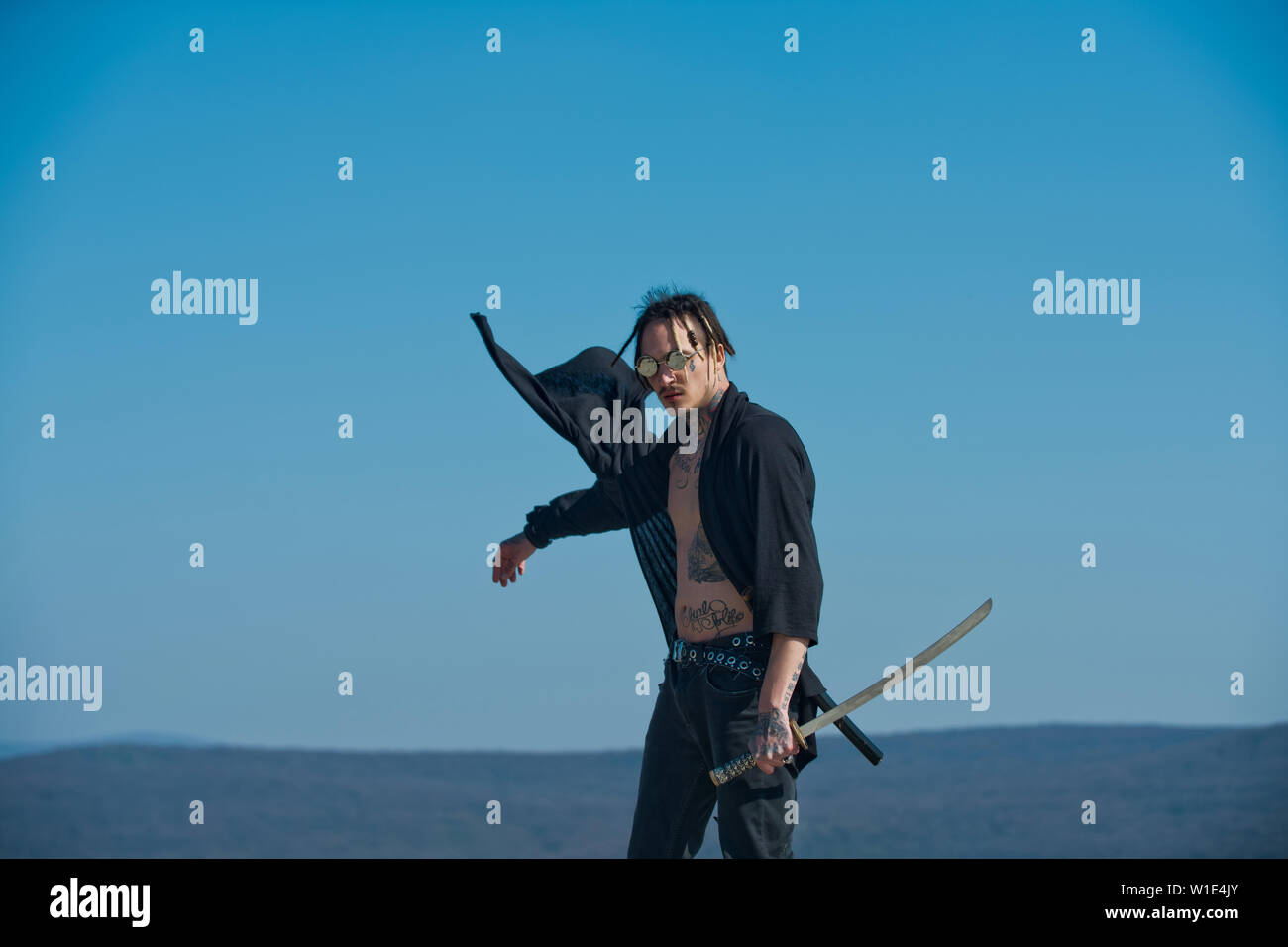 Warrior with dreadlocks and open clothes showing tattooed torso. Man with  katana sword standing on blue sky. Martial arts concept. Samurai and japan  w Stock Photo - Alamy