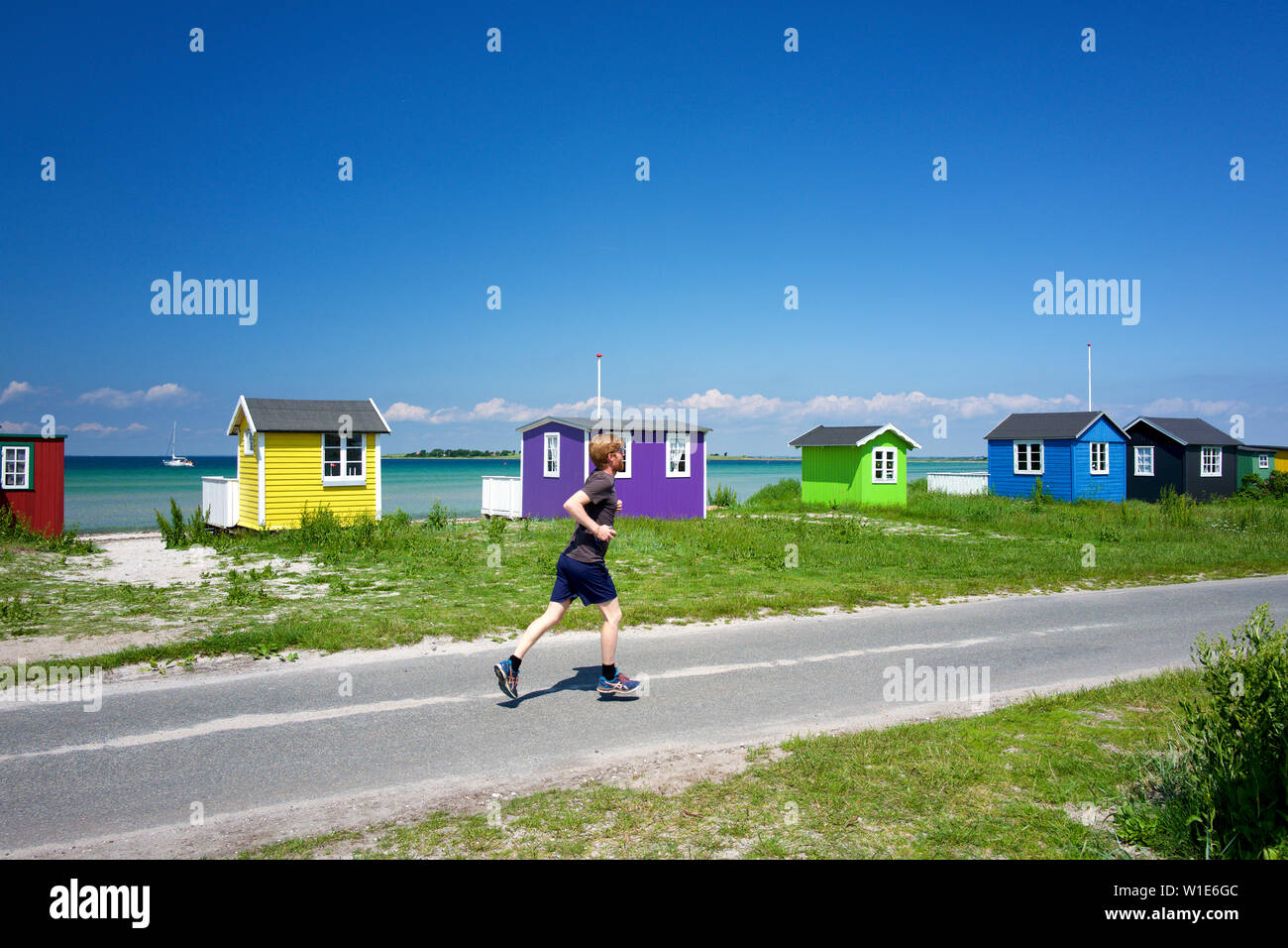 Running past beach huts, Aeroskobing, Aero, Denmark Stock Photo
