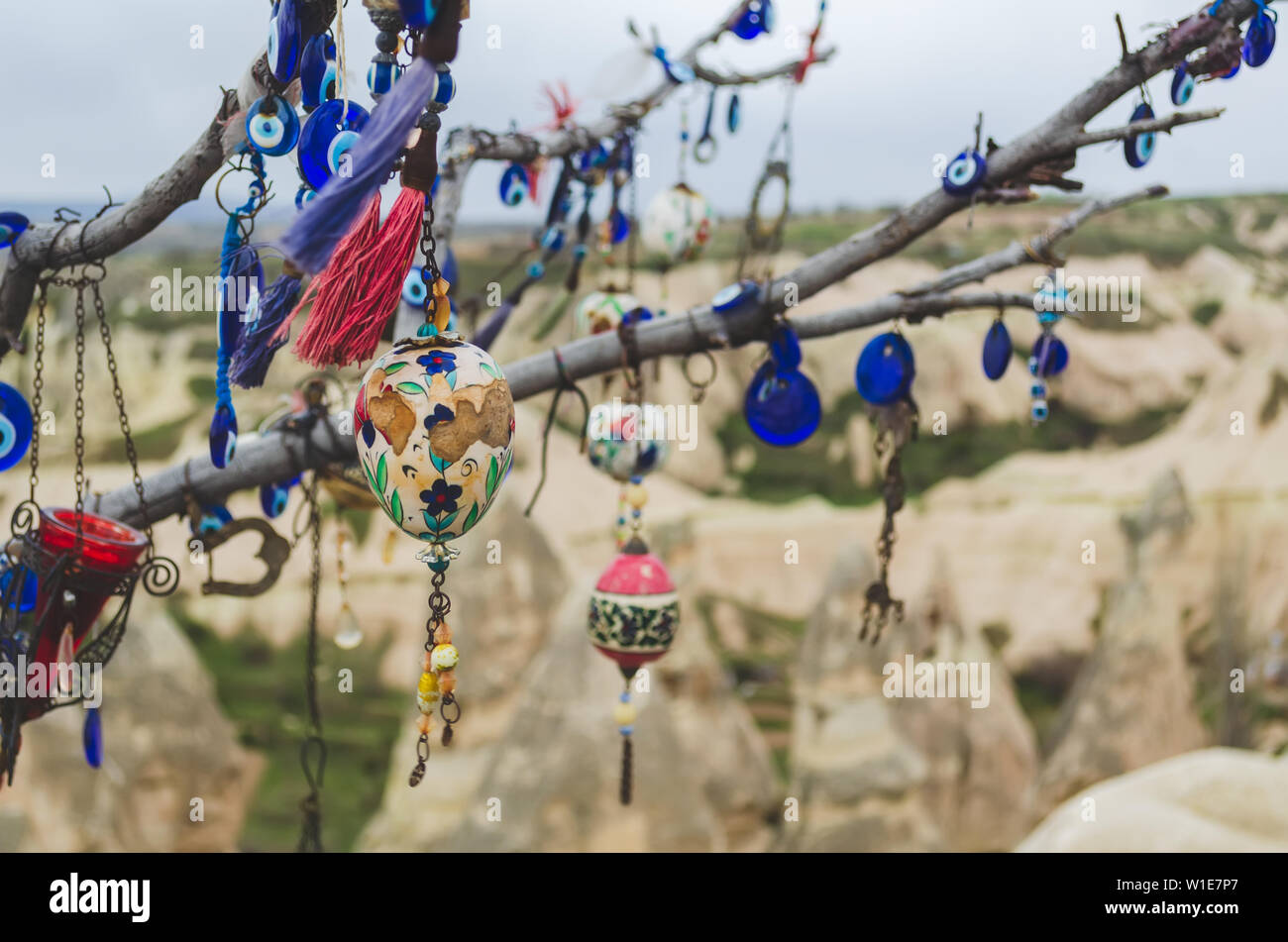 Traditional Turkish amulets and decorations hang on the branches of a wishes tree against the backdrop of the volcanic landscape of Cappadocia Stock Photo