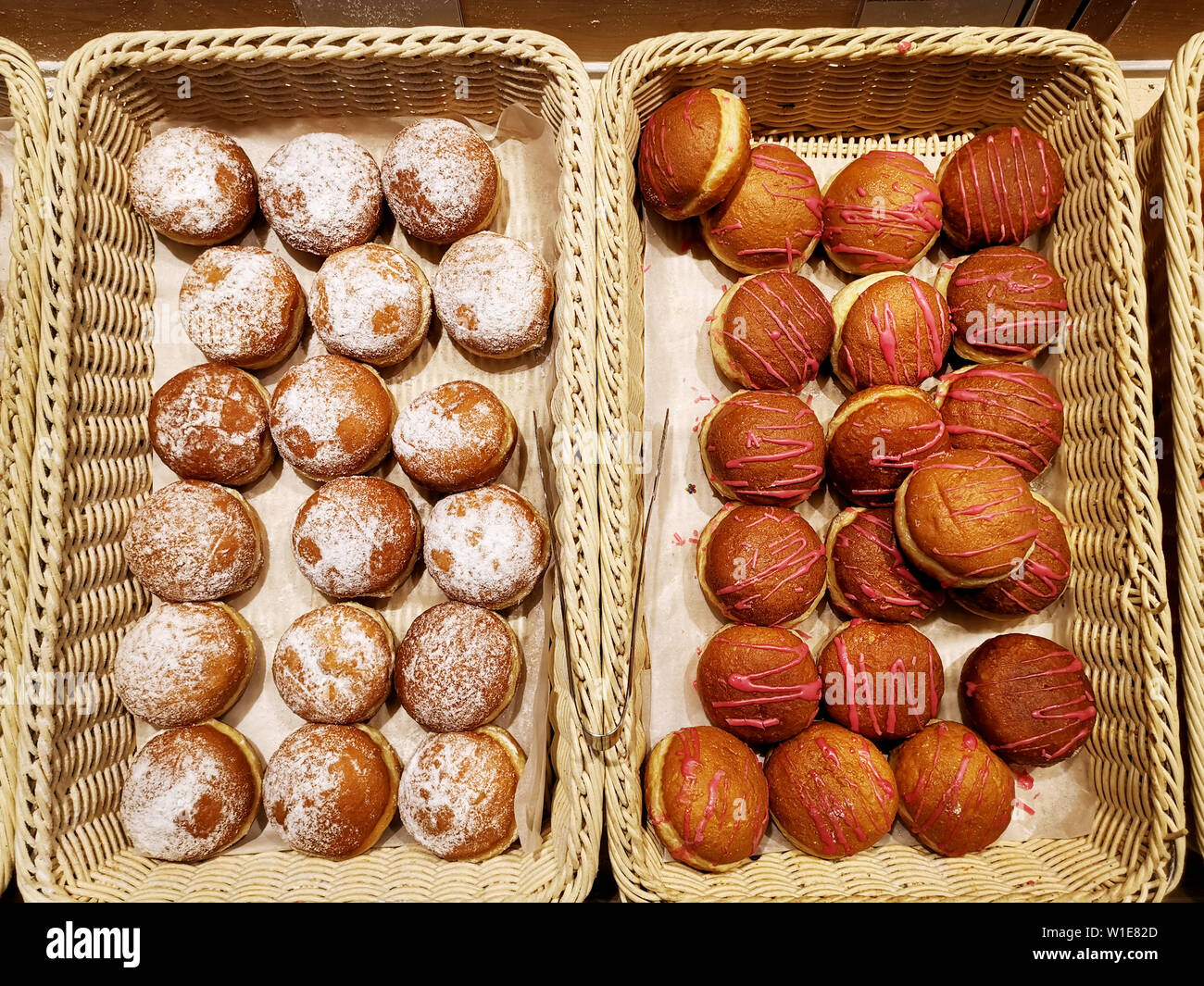 Assorted sweet donuts, glazed and iced and powdered pastries in baskets