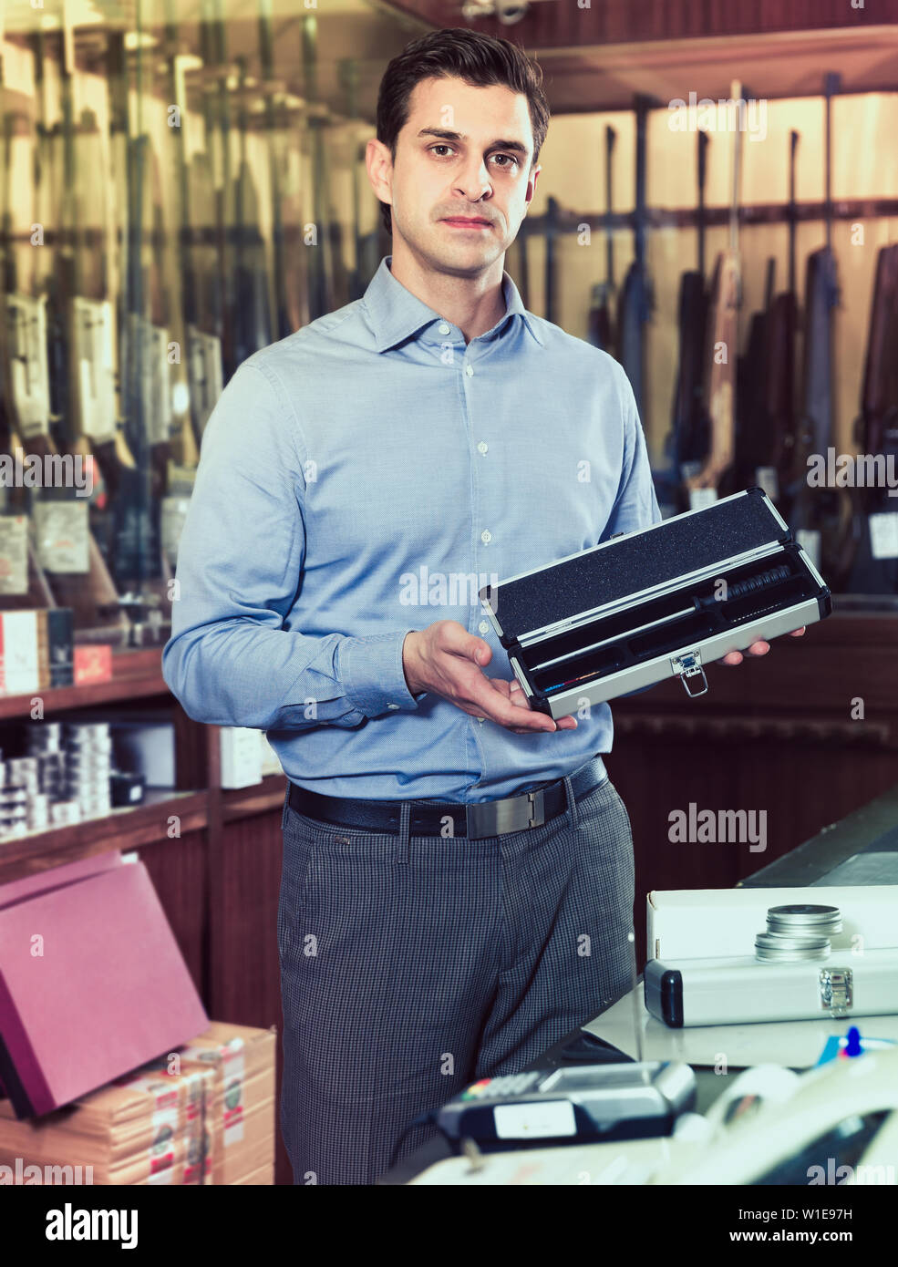 Positive male owner of hunting shop offering ammunition and accessories ...