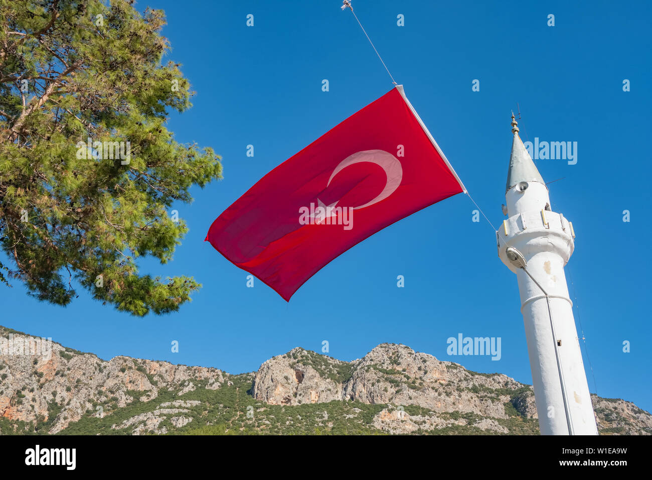 Turkish national flag and white minaret in Kas, Turkey. Stock Photo