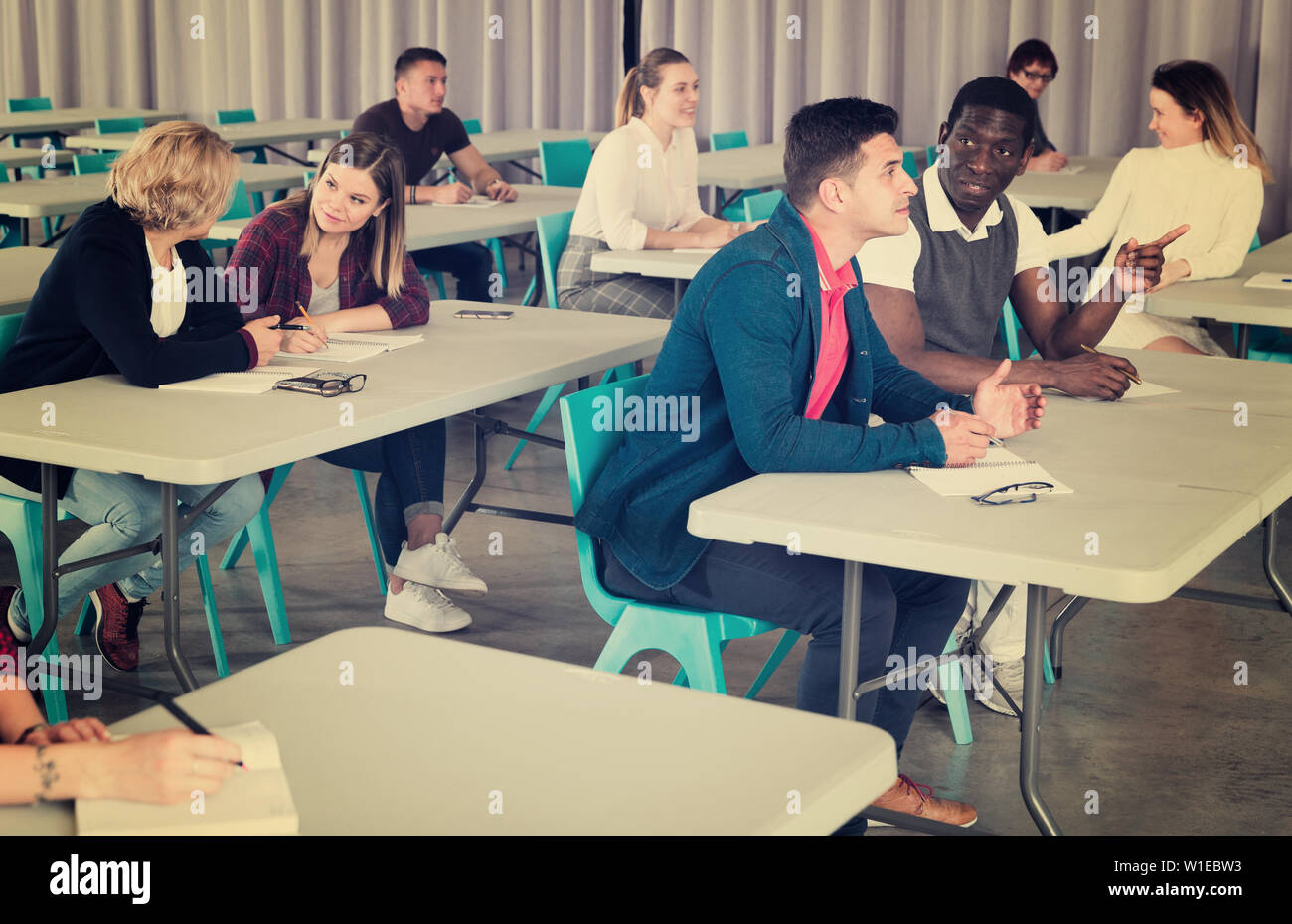 Group of adult education students studying together in class ...