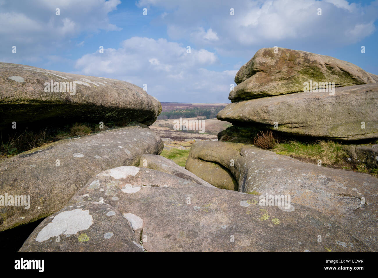 Millstone grit rocks or boulders at Over Owler Tor in the Peak District pointing to a view overlooking moorland Stock Photo