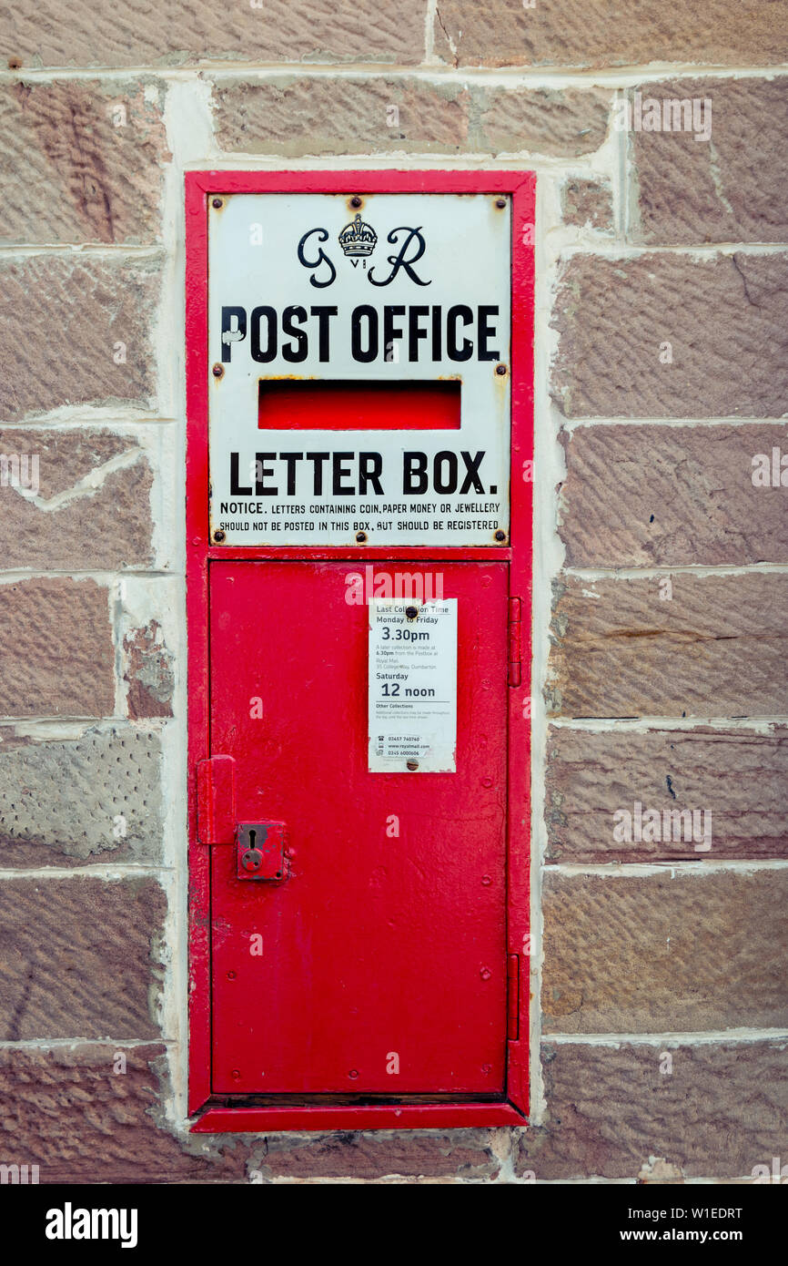 A traditional vintage Georgian bright red letter box or postbox built into a brick wall Stock Photo