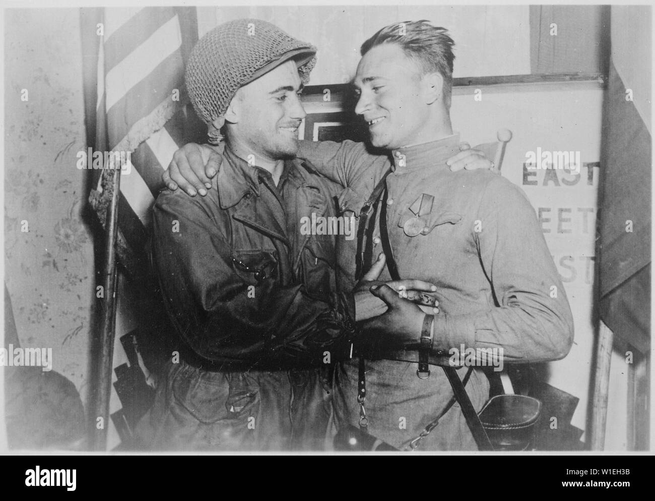 Happy 2nd Lieutenant William Robertson and Lt. Alexander Sylvashko, Russian Army, shown in front of sign [East Meets West] symbolizing the historic meeting of the Russian and American Armies, near Torgau, Germany.; General notes:  Use War and Conflict Number 1096 when ordering a reproduction or requesting information about this image. Stock Photo