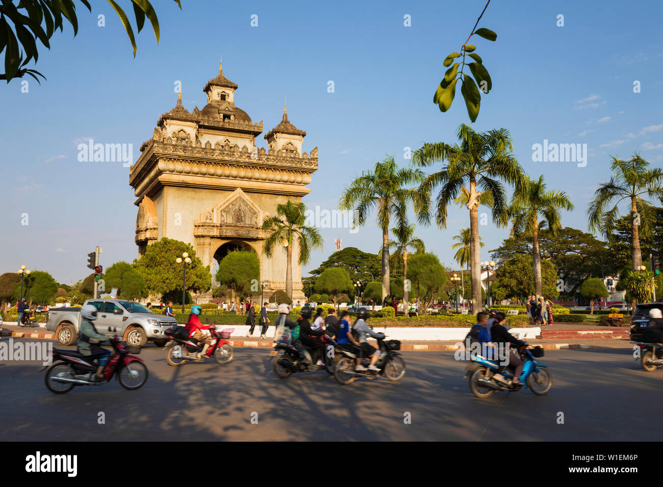 Mopeds riding past the Patuxai Victory Monument (Vientiane Arc de Triomphe), Vientiane, Laos, Indochina, Southeast Asia, Asia Stock Photo