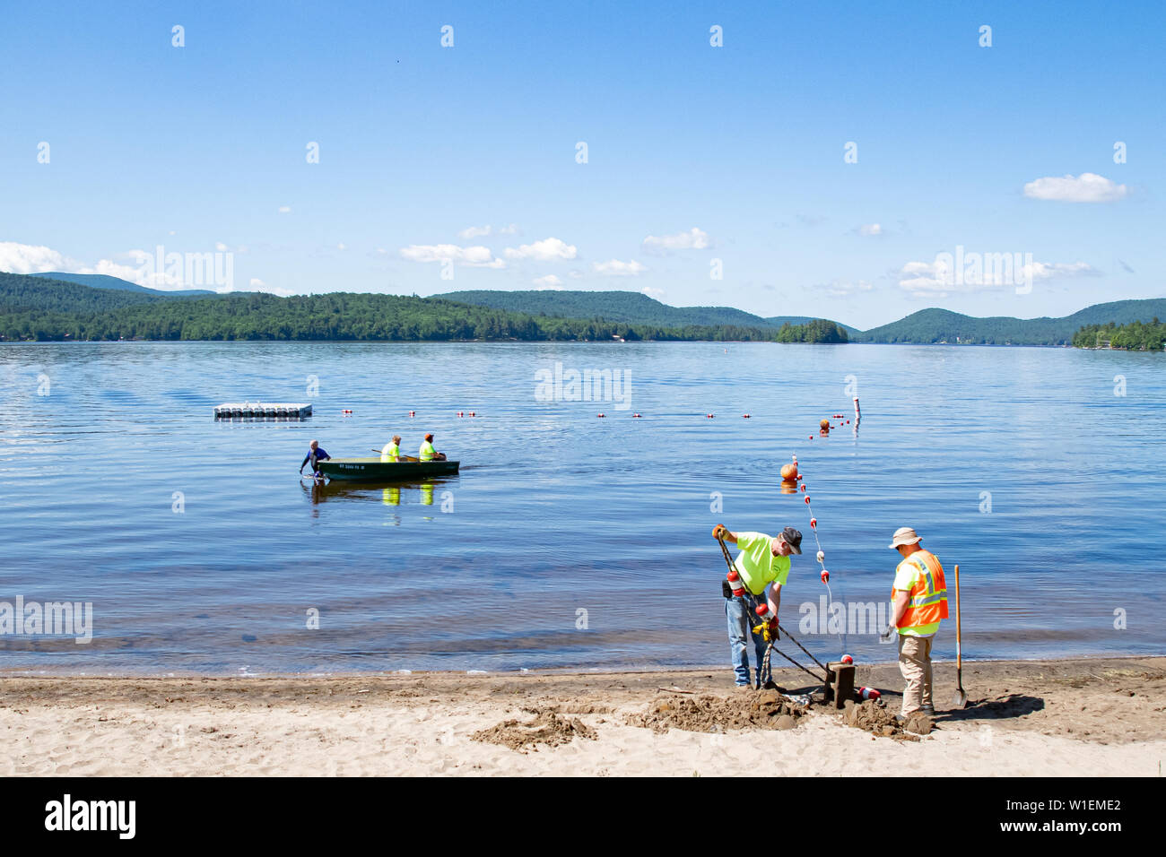 Workers setting up a swimming area at the Village of Speculator, NY USA beach on Lake Pleasant. Stock Photo