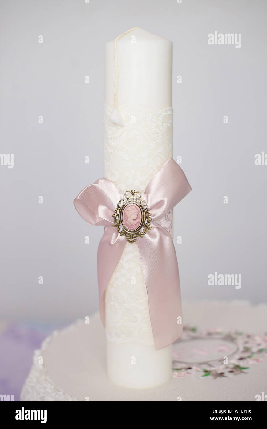 Baptismal delicate white candle wrapped with a pink ribbon cameo, in  preparation for the baptism, first of seven Sacraments in the Orthodox  Church Stock Photo - Alamy