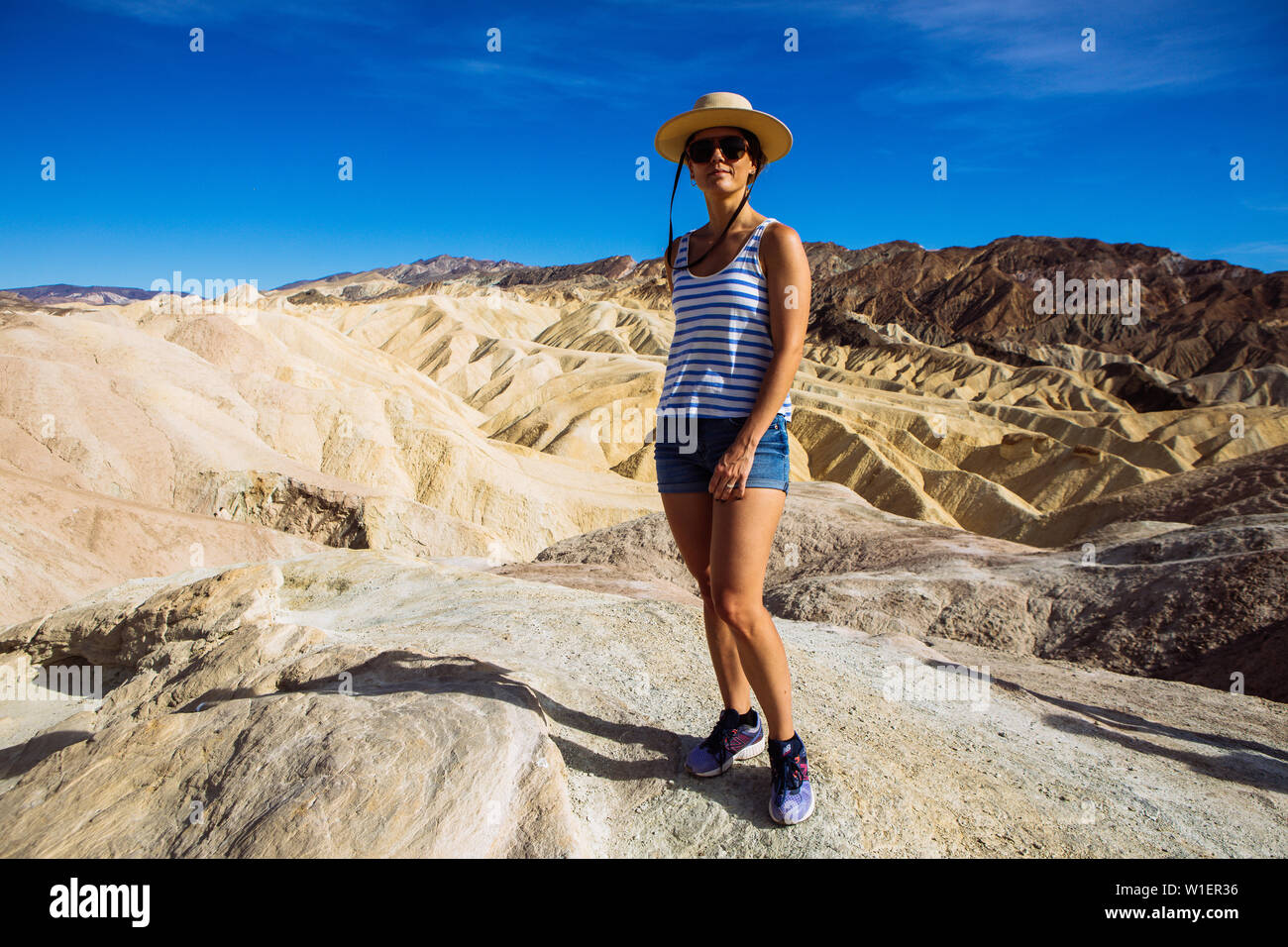 Tourist woman posing with hat and shades at Zabriskie Point, Furnace Creek, Death Valley National Park, California, USA Stock Photo
