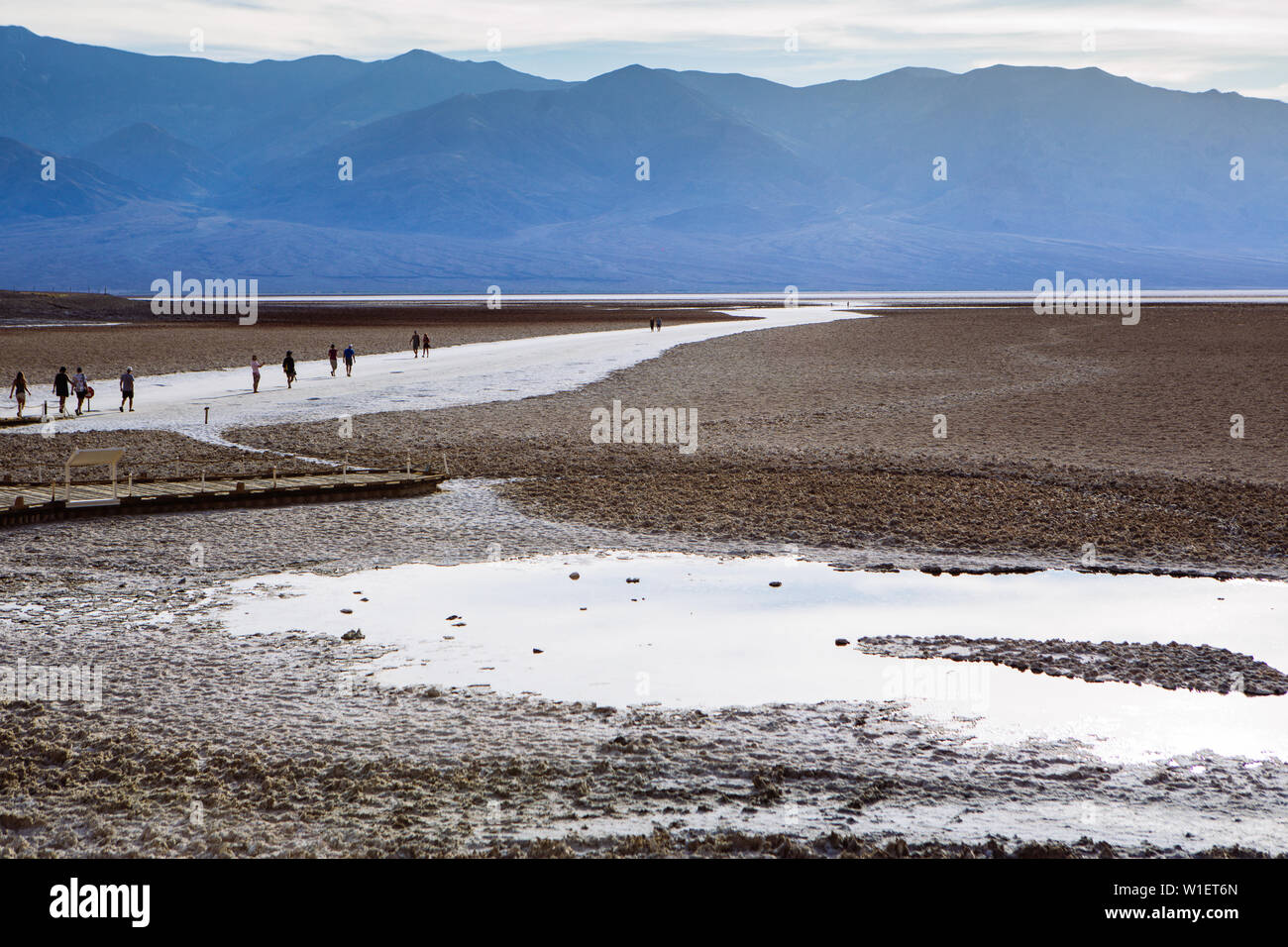 Side view of people walking across a path in Badwater basin, endorheic basin, Death Valley National Park, Inyo, California, USA Stock Photo