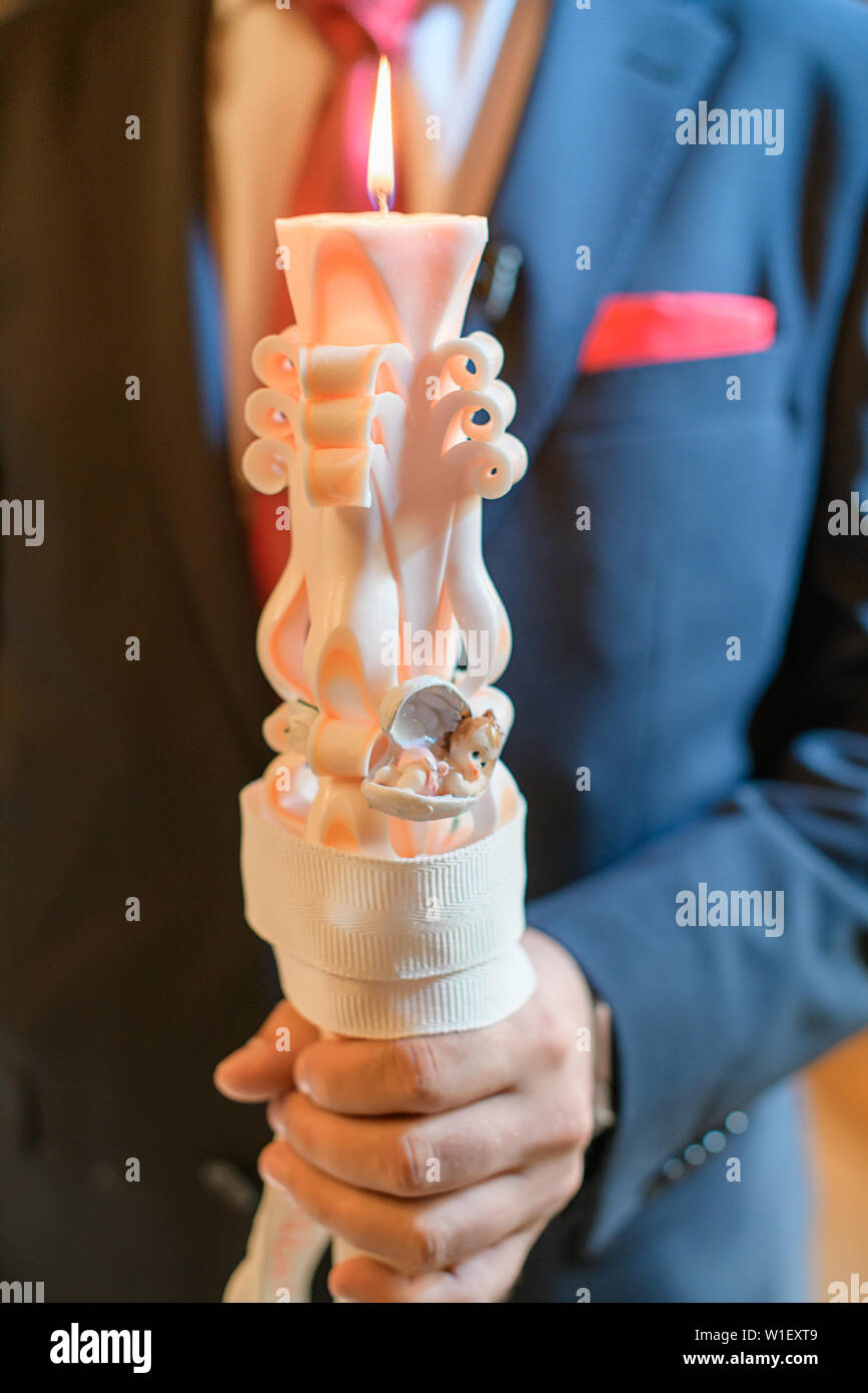 Man holding an embellished baptismal candle in an Orthodox church in preparation for the baptism
