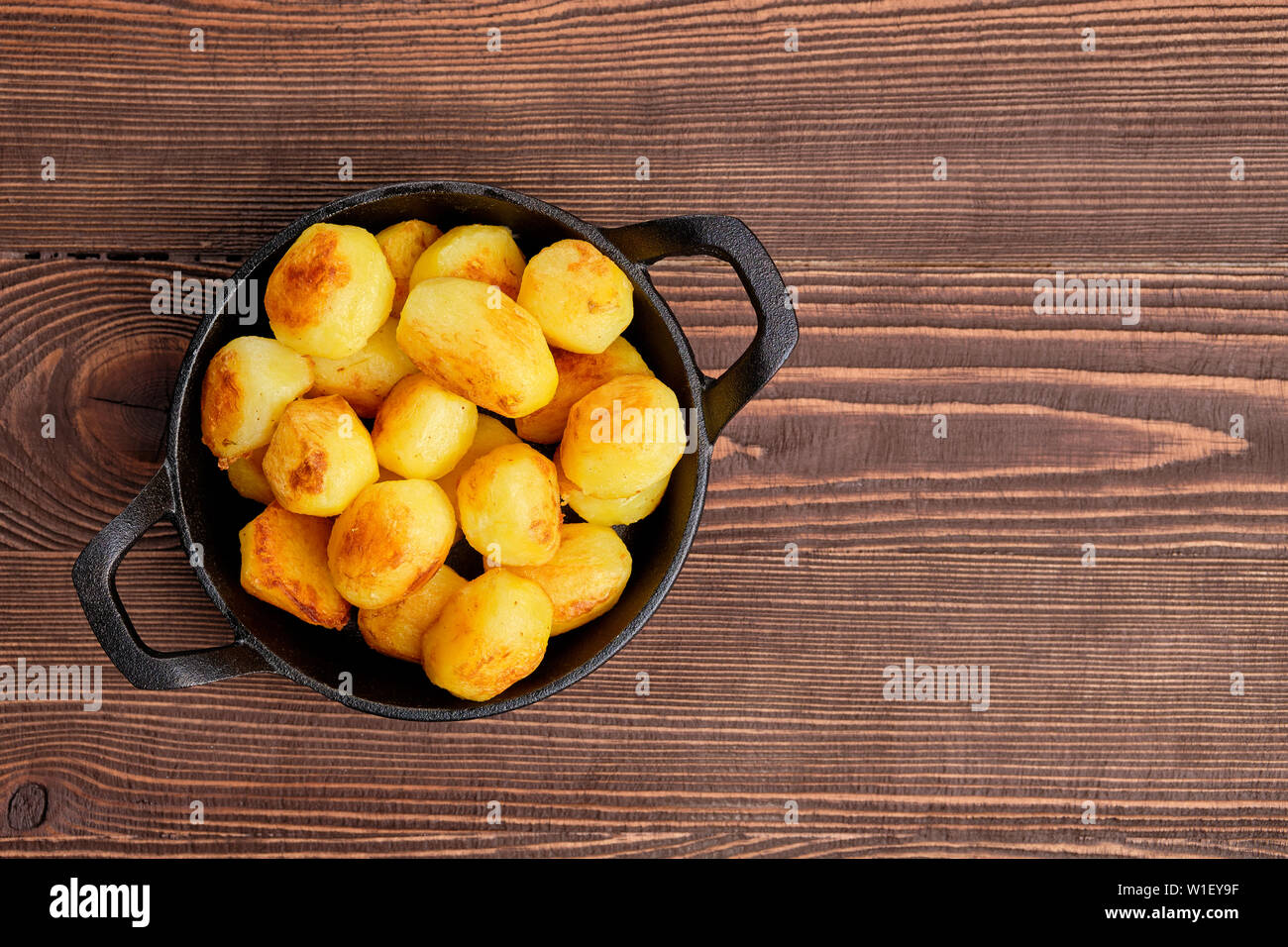 https://c8.alamy.com/comp/W1EY9F/baked-potato-in-cast-iron-skillet-on-natural-wooden-background-W1EY9F.jpg