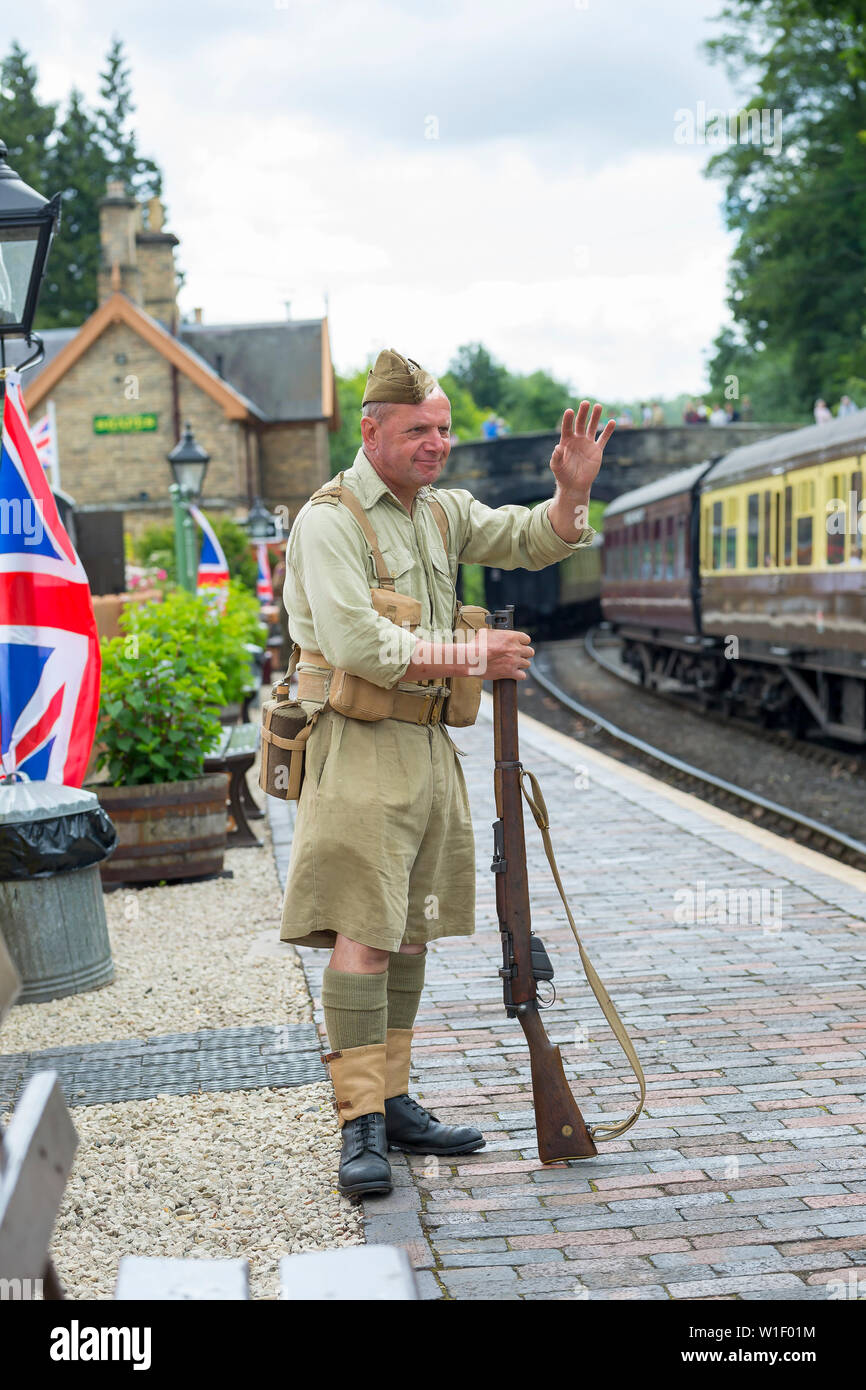 Kidderminster, UK. 29th June, 2019. Severn Valley Railways 'Step back to the 1940's' gets off to a fabulous start this weekend with costumed re-enactors playing their part in providing an authentic recreation of wartime Britain. Man in British army uniform waves at vintage train leaving Arley station to the sound of 'We'll Meet Again'. Credit: Lee Hudson Stock Photo