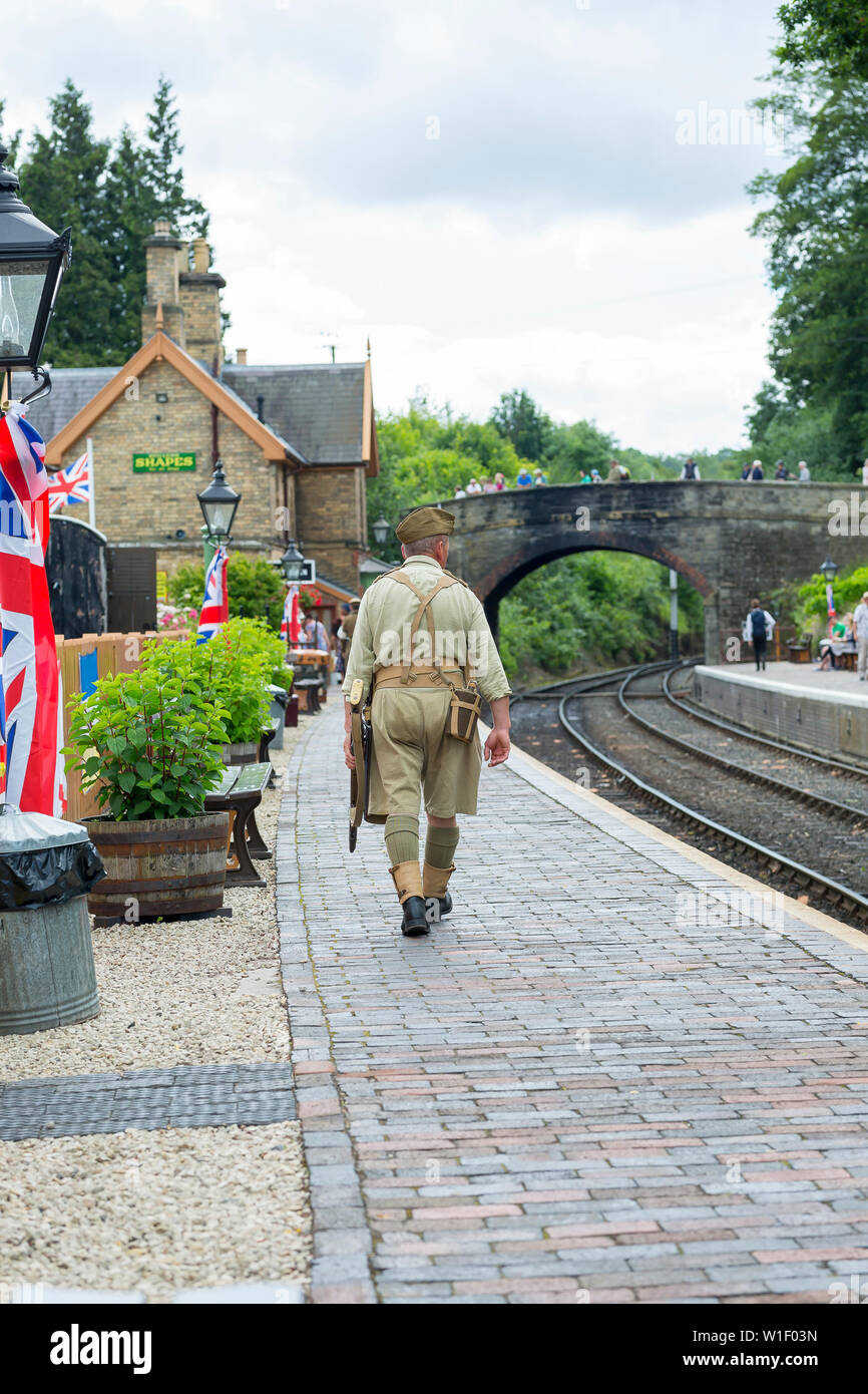 Kidderminster, UK. 29th June, 2019. Severn Valley Railways 'Step back to the 1940's' gets off to a fabulous start this weekend with costumed re-enactors playing their part in providing an authentic recreation of wartime Britain. The rear view of a man in uniform is captured here as he walks down the platform at Arley's rural train station. Credit: Lee Hudson Stock Photo