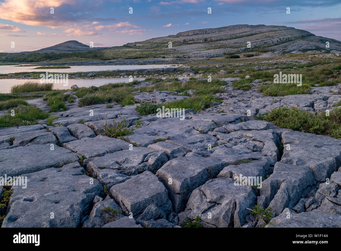 A sunset shot of the stunning and mars like landscape that is The Burren National Park, County Clare, Ireland with small lake in the foreground, nobod Stock Photo