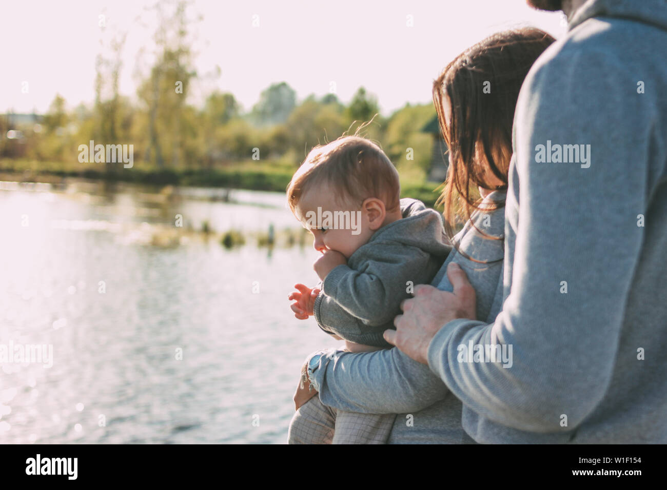Happy family with Cute baby boy on the lake water background outdoors