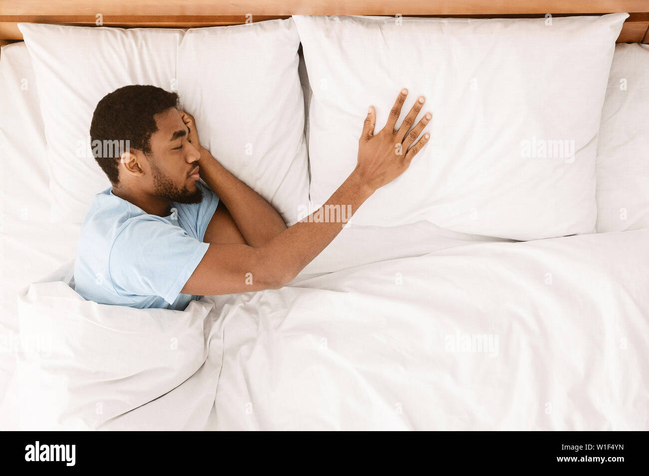Lonely black man sleeping in bed and missing his partner Stock Photo