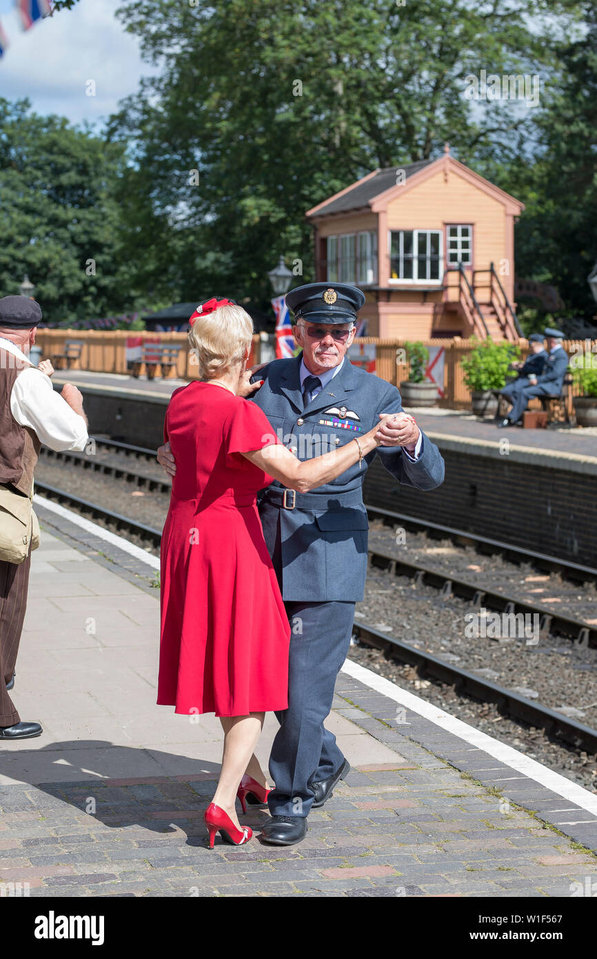 Kidderminster, UK. 29th June, 2019. Severn Valley Railways 'Step back to the 1940s' gets off to a fabulous start this weekend with costumed re-enactors playing their part in providing an authentic recreation of wartime Britain. A smartly-dressed couple in 1940's fashion are dancing together on the platform of a vintage railway station in the morning sunshine. Credit: Lee Hudson Stock Photo