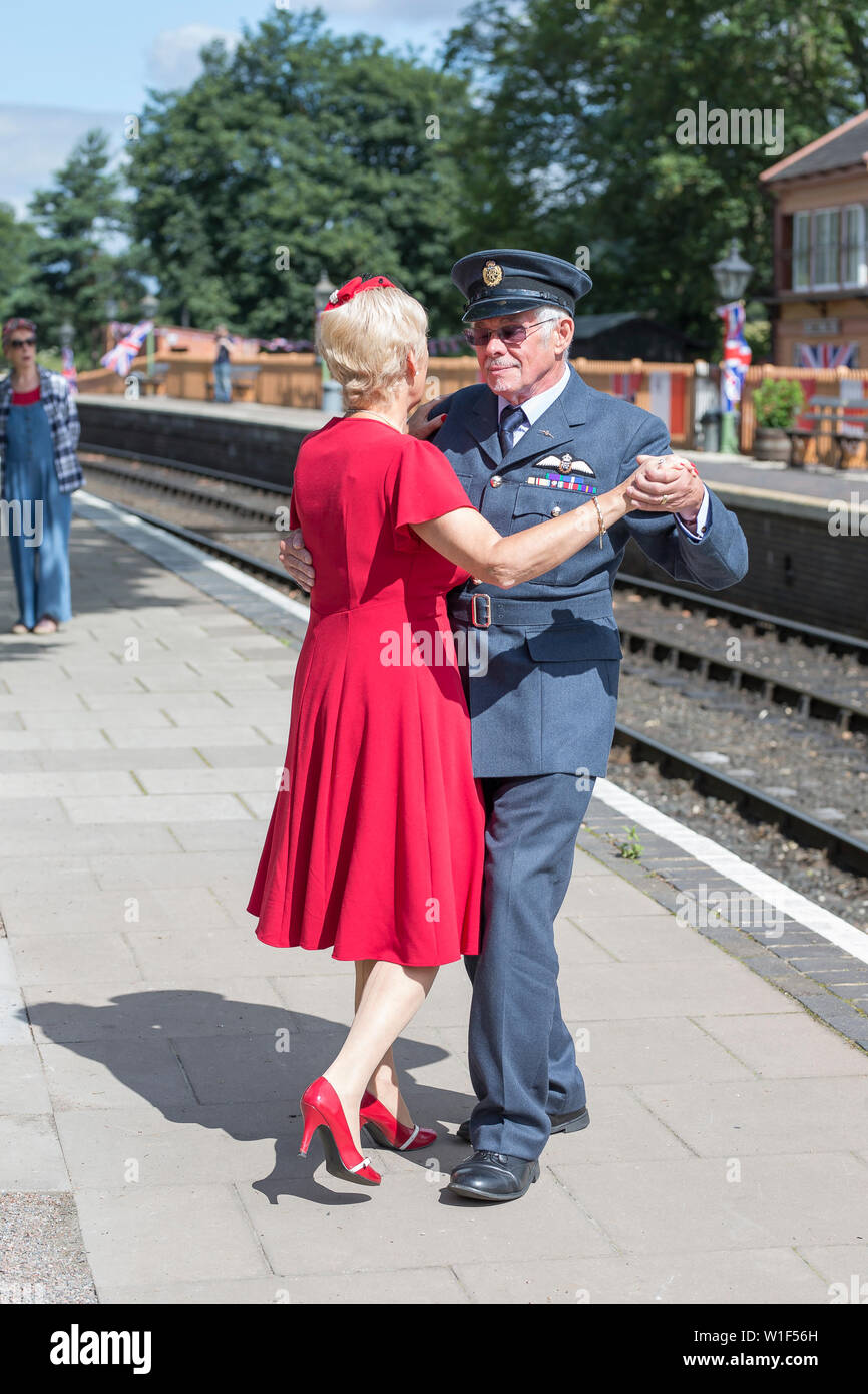 Kidderminster, UK. 29th June, 2019. Severn Valley Railways 'Step back to the 1940s' gets off to a fabulous start this summer weekend with costumed re-enactors playing their part in providing an authentic recreation of wartime Britain. A smartly-dressed couple in 1940's fashion are dancing together on the platform of a vintage railway station in the morning sunshine. Credit: Lee Hudson Stock Photo