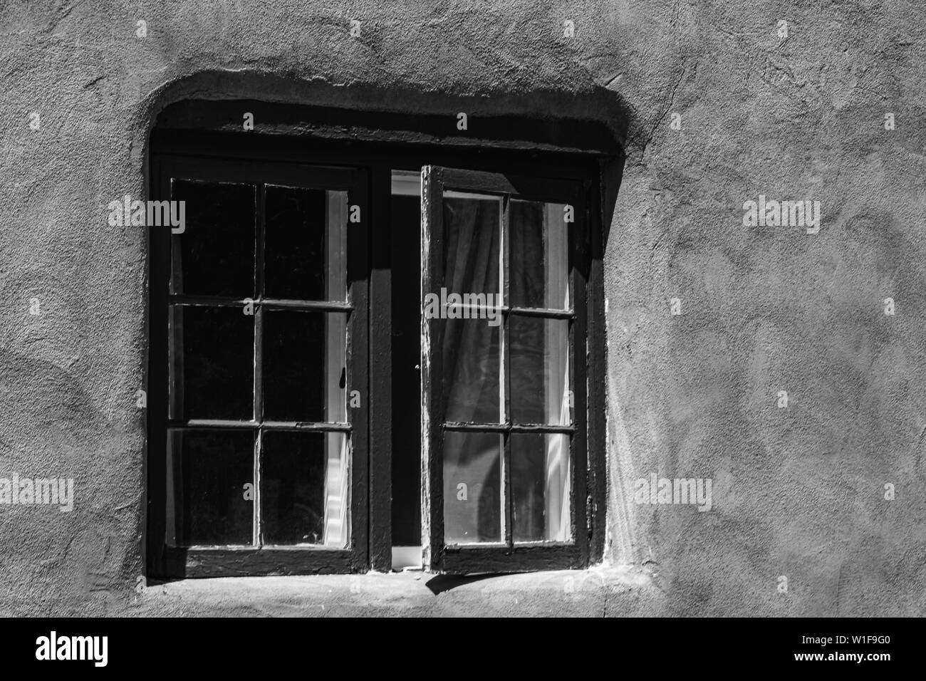 Wooden framed window in an old stucco building in New Mexico, black and