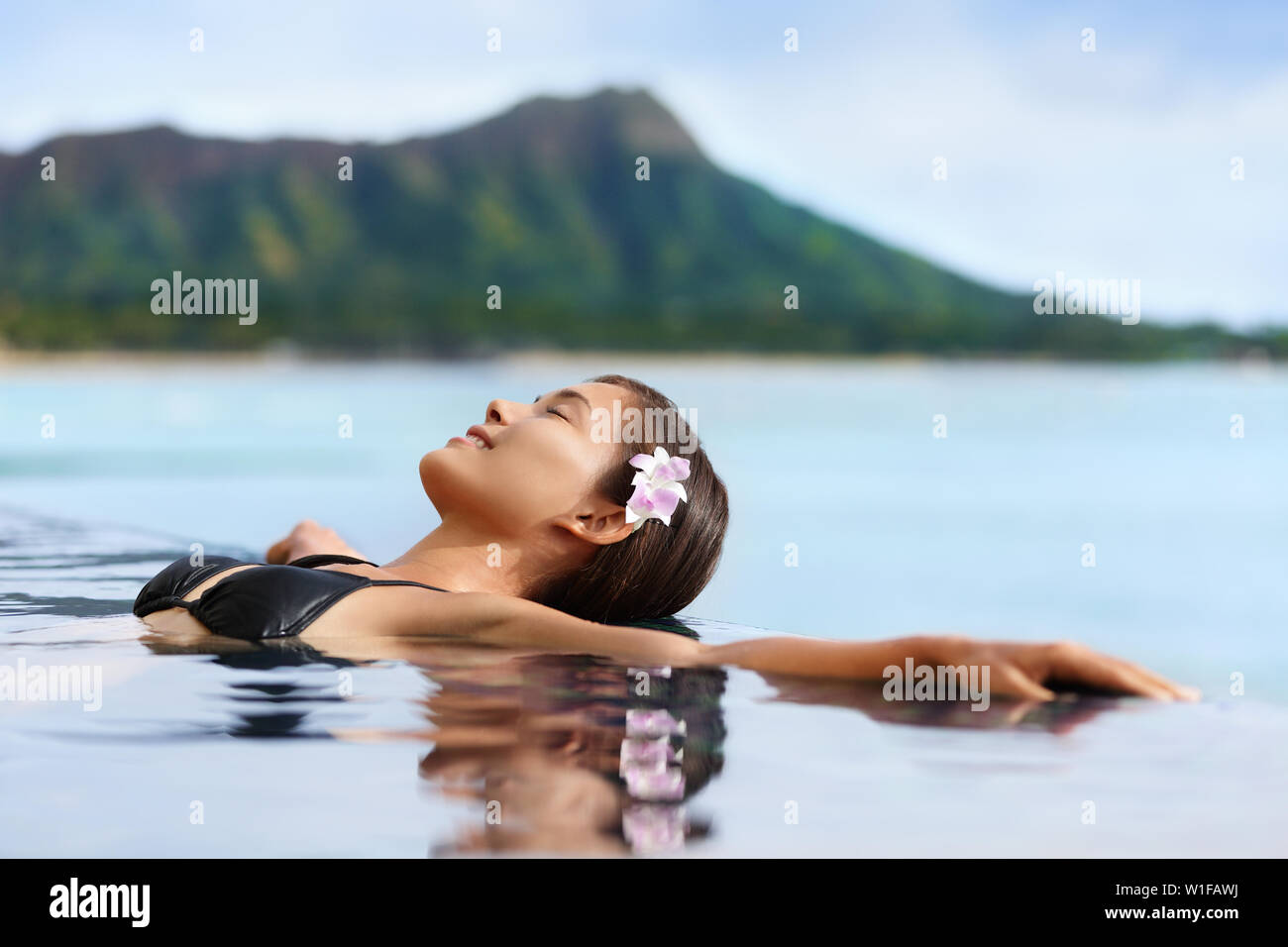 Hawaii vacation wellness pool spa woman relaxing in warm water at luxury hotel resort. Young adult at Waikiki beach in Honolulu, Oahu, Hawaii, USA. Stock Photo