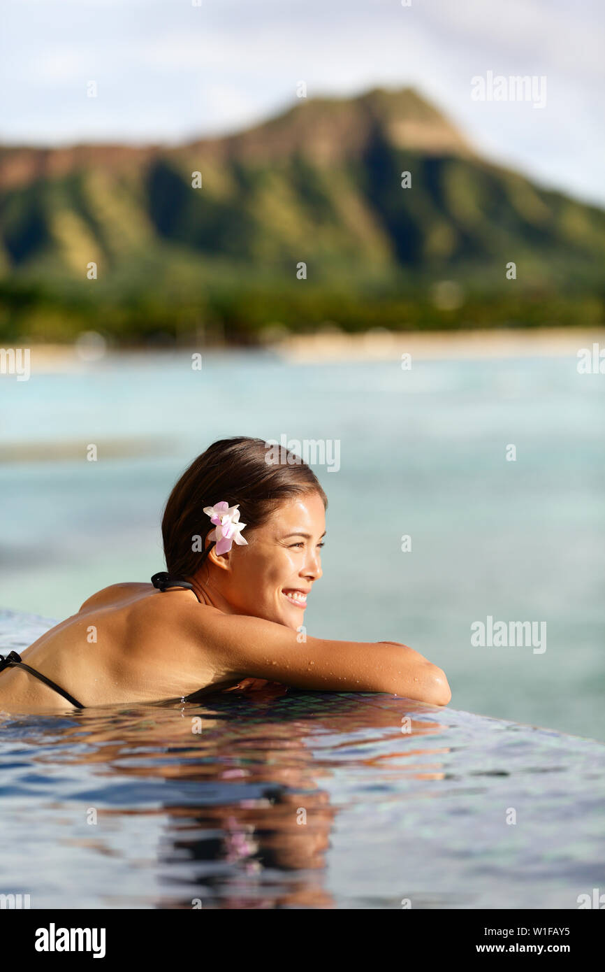 Travel vacations woman on holiday at beach resort hotel pool. Beautiful asian young adult relaxing in the sun on Waikiki, Oahu, Honolulu, Hawaii. USA vacation destination. Stock Photo