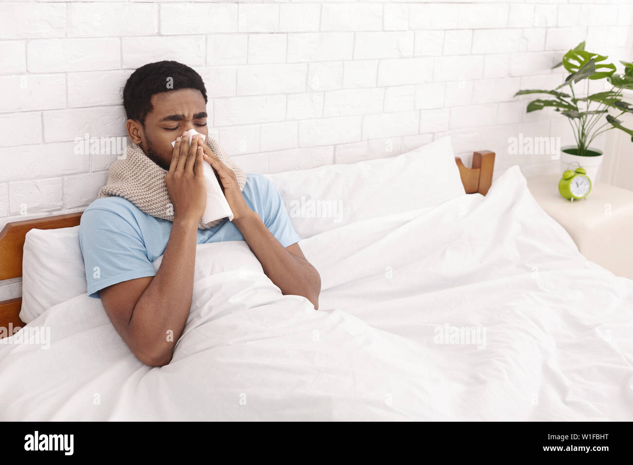 Young sick man in bed cleaning snotty nose Stock Photo Alamy