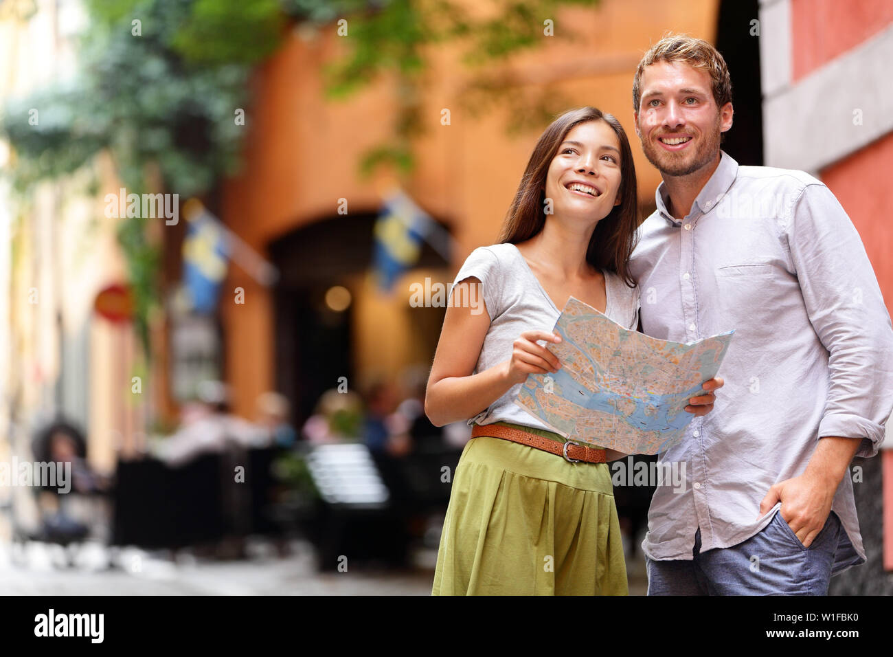 Stockholm tourists couple looking at map. Europe tourism people walking in Swedish street in Gamla Stan the old town of Stockholm, Sweden. Stock Photo