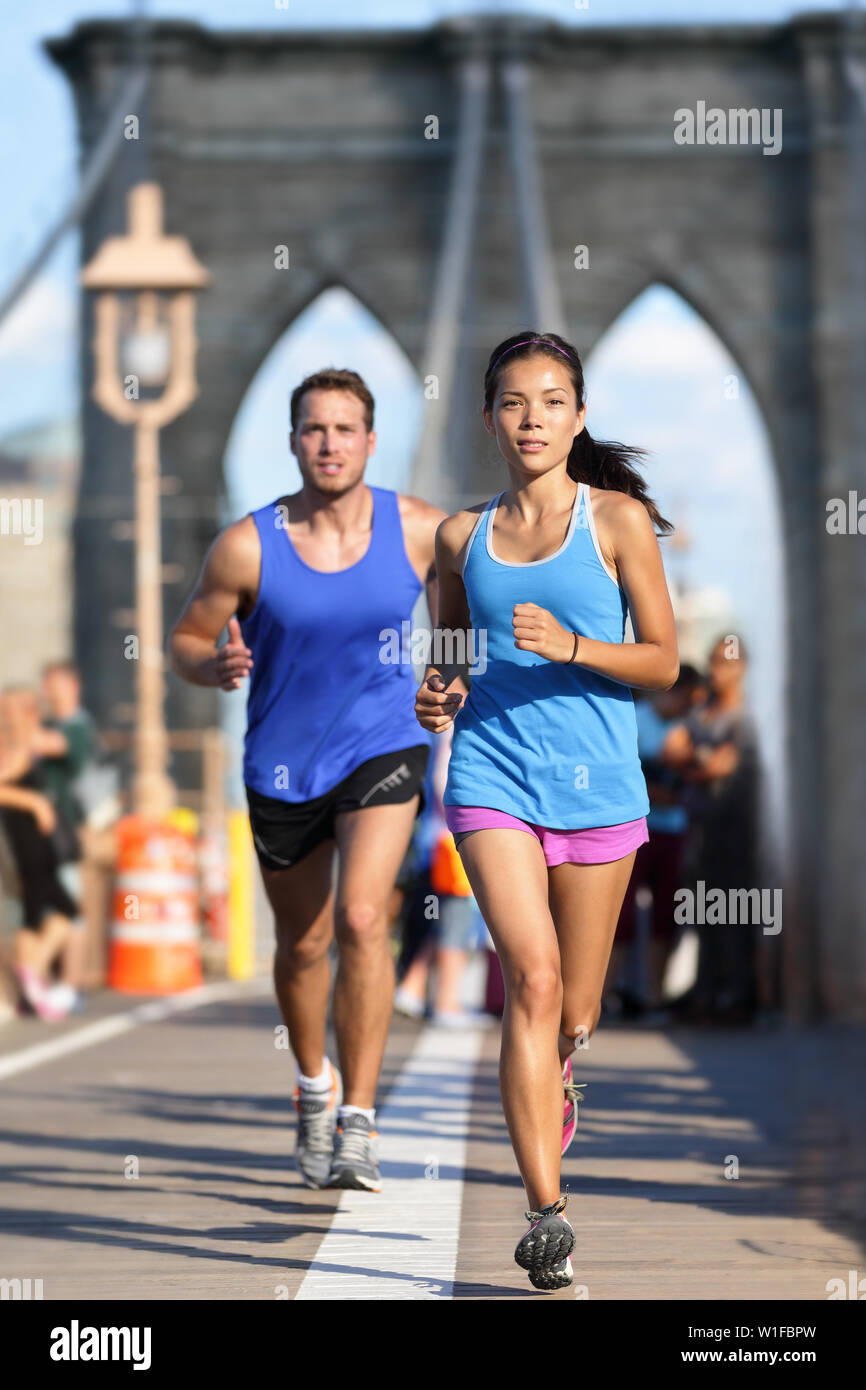 New York runners running training on Brooklyn bridge NYC during busy rush hours with tourists