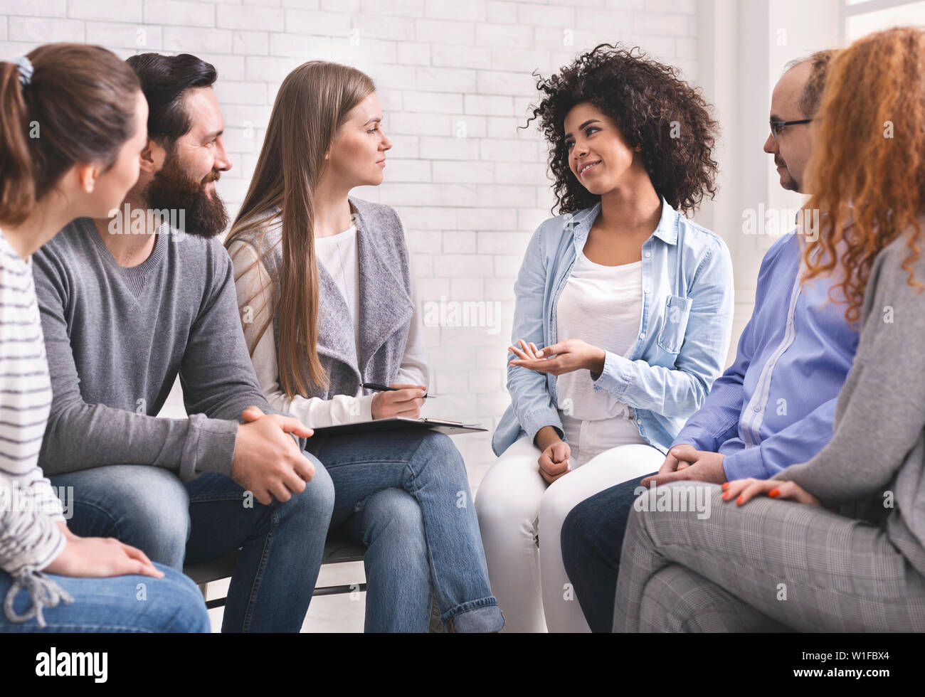 Cheerful african woman sharing her achievements at group therapy Stock Photo