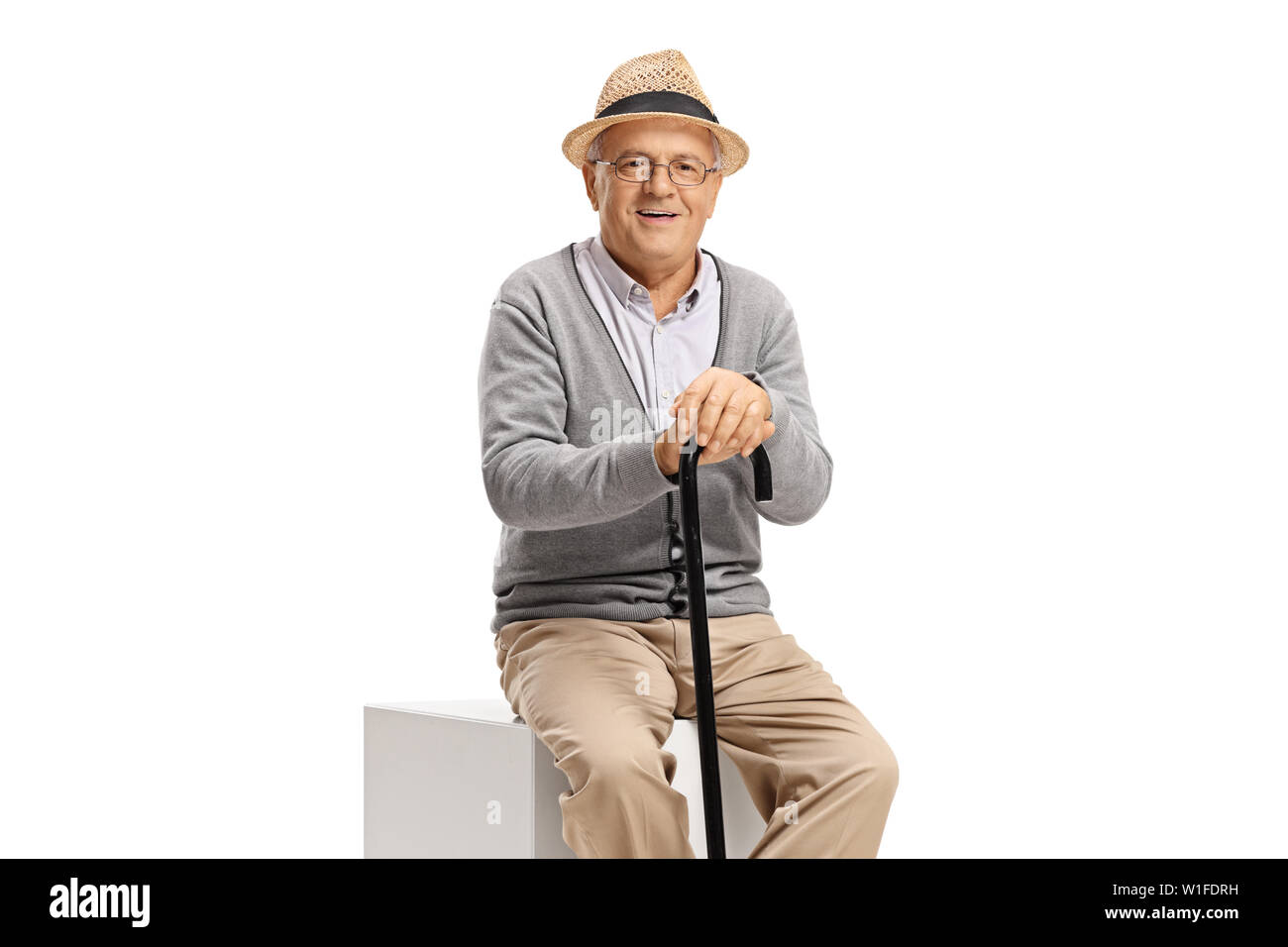 Elderly man with a cane sitting and looking at the camera isolated on ...