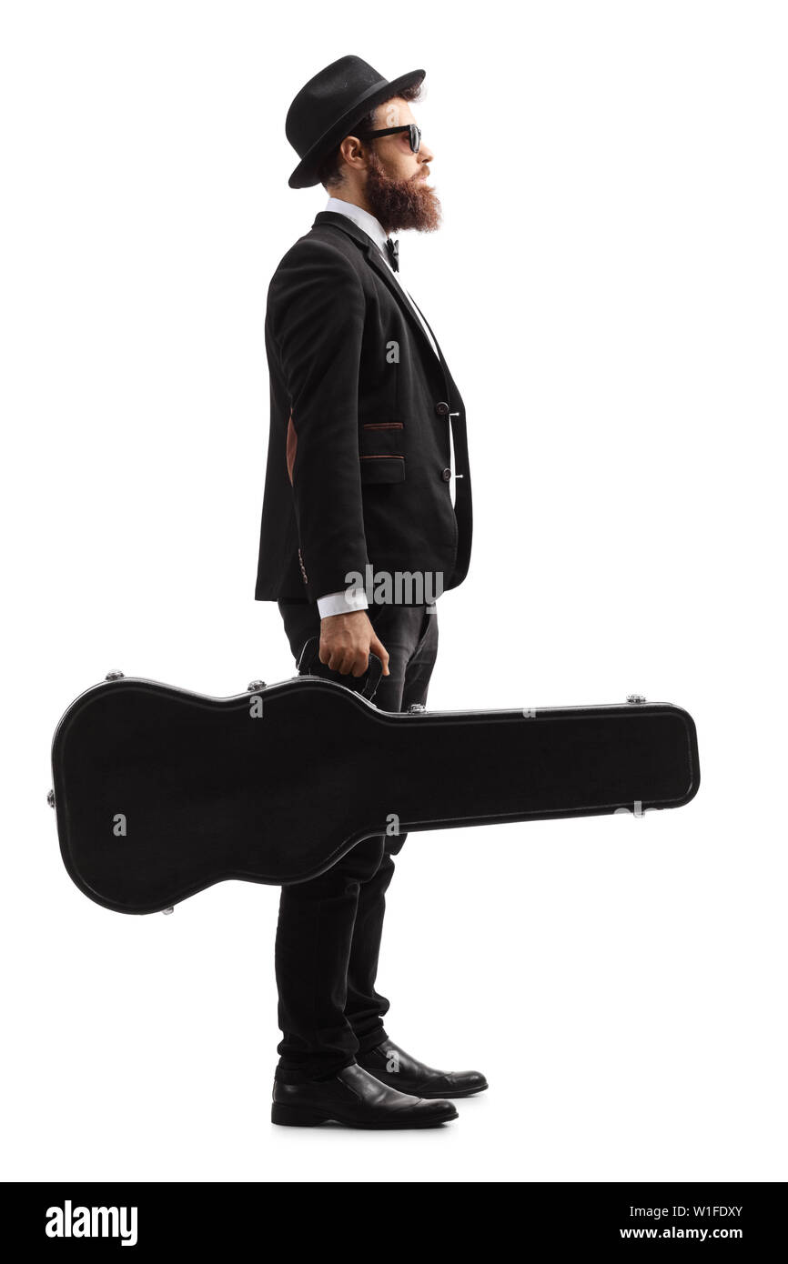 Full length profile shot of a male musician standing and holding a guitar in a black case isolated on white background Stock Photo