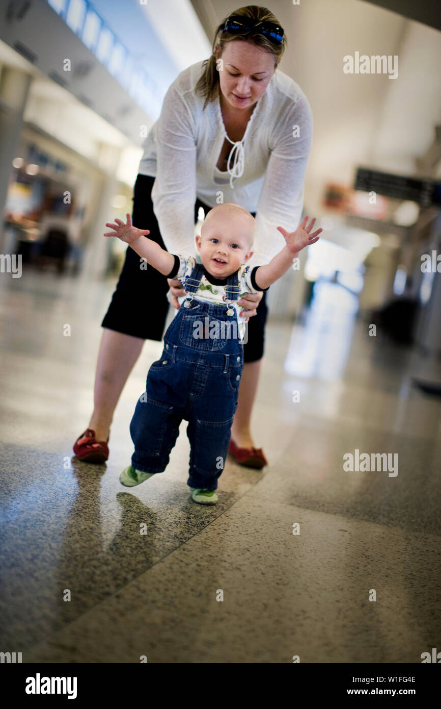 Mother helping baby son to walk in an airport Stock Photo - Alamy