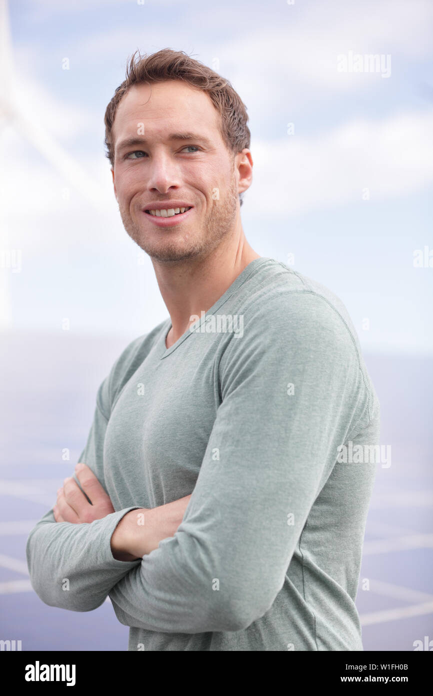 Portrait of young man entrepreneur solar panels outdoors. Casual young business man standing proud outside. Stock Photo