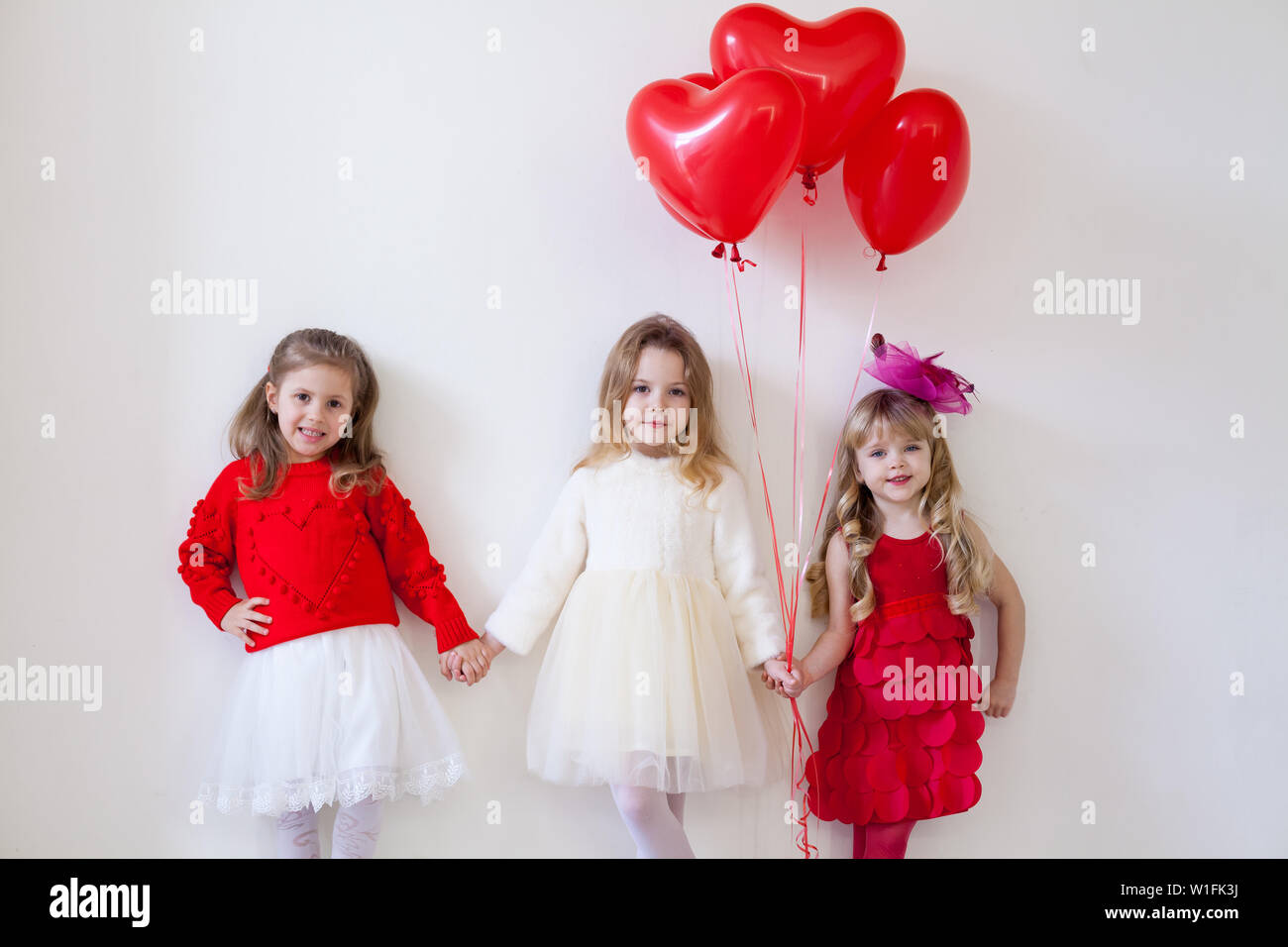 Three little beautiful girls in red hold hands Stock Photo - Alamy