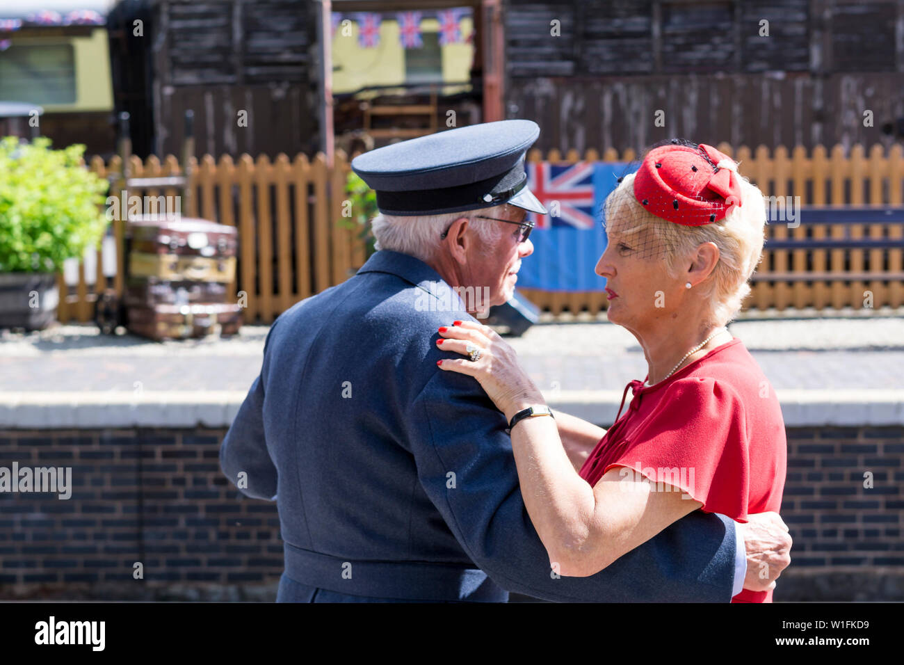 Kidderminster, UK. 29th June, 2019. Severn Valley Railways 'Step back to the 1940's' gets off to a fabulous start this weekend with costumed re-enactors playing their part in providing an authentic recreation of wartime Britain. A smartly-dressed couple in 1940's fashion are dancing together on the platform of a vintage railway station in the morning sunshine. Credit: Lee Hudson Stock Photo